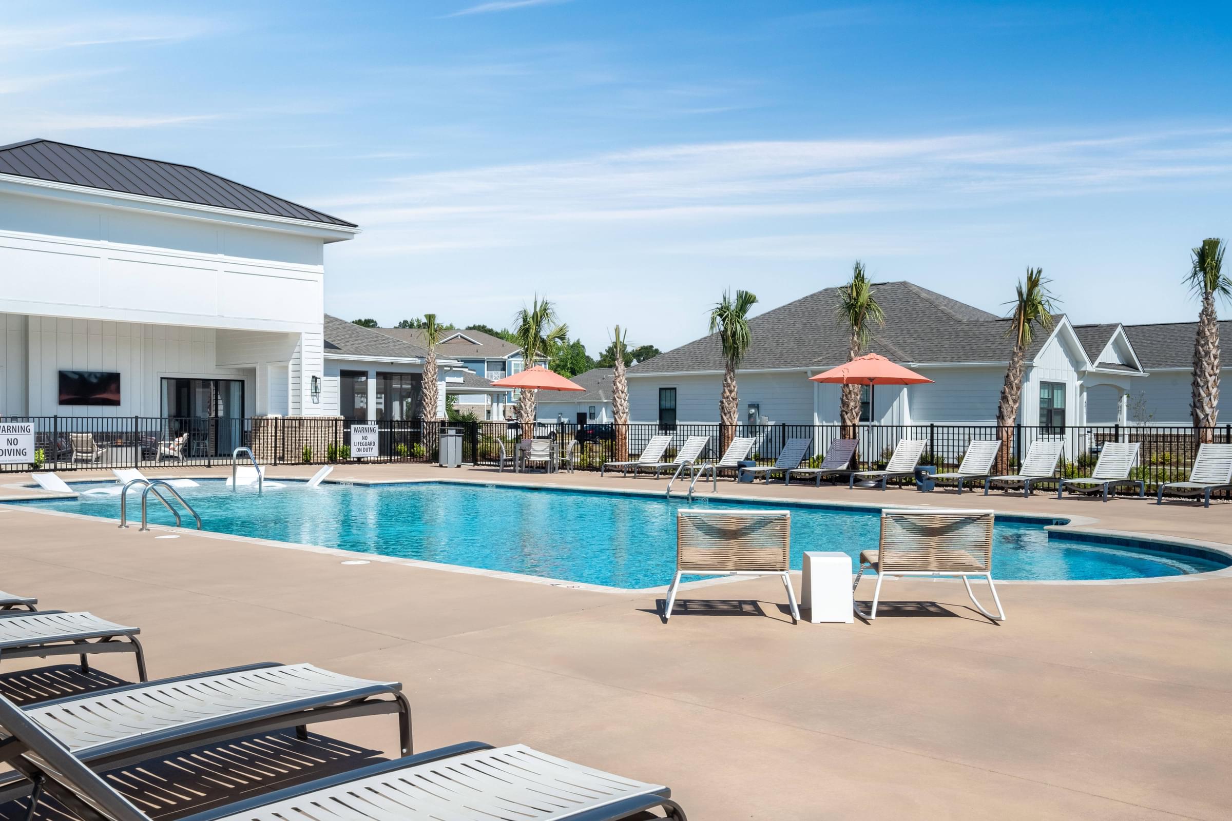 A pool area with lounge chairs and a building in the background.