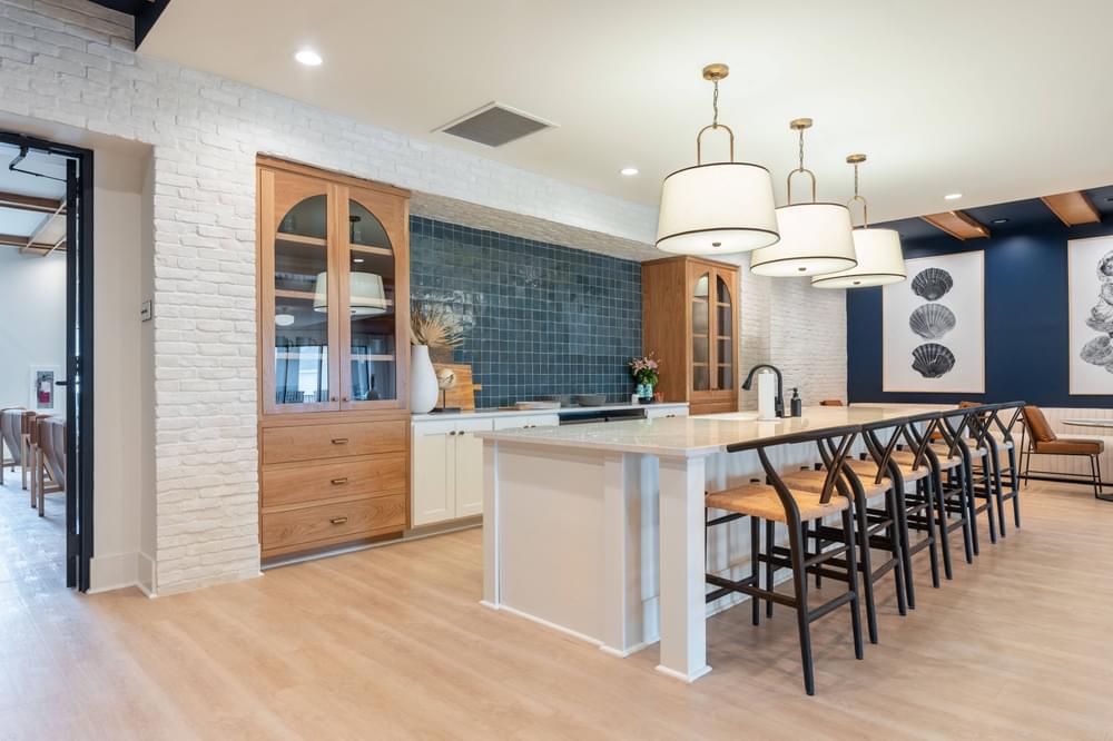 a large white kitchen with a long island and chairs