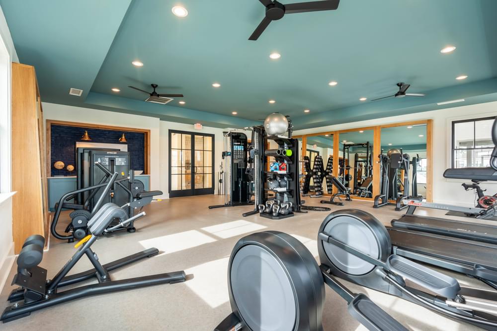 a home gym with weights and cardio equipment and windows