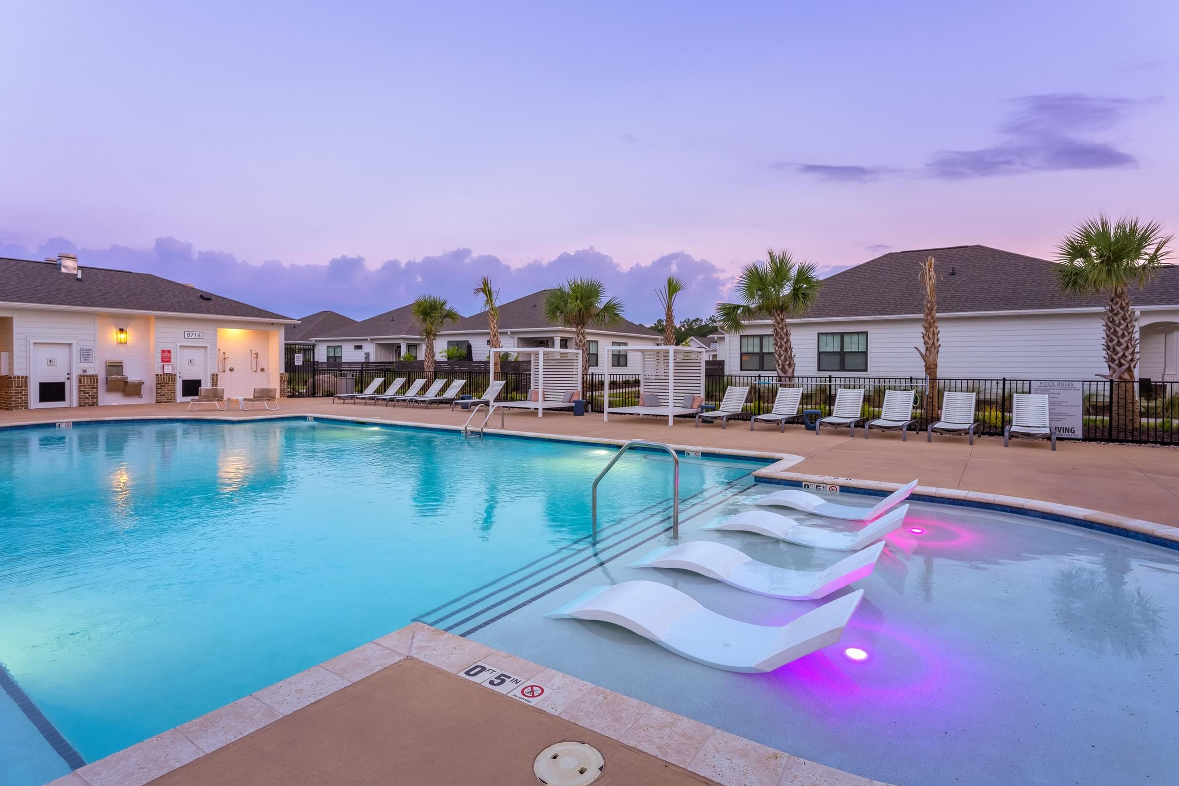 A swimming pool with lounge chairs and a purple light.