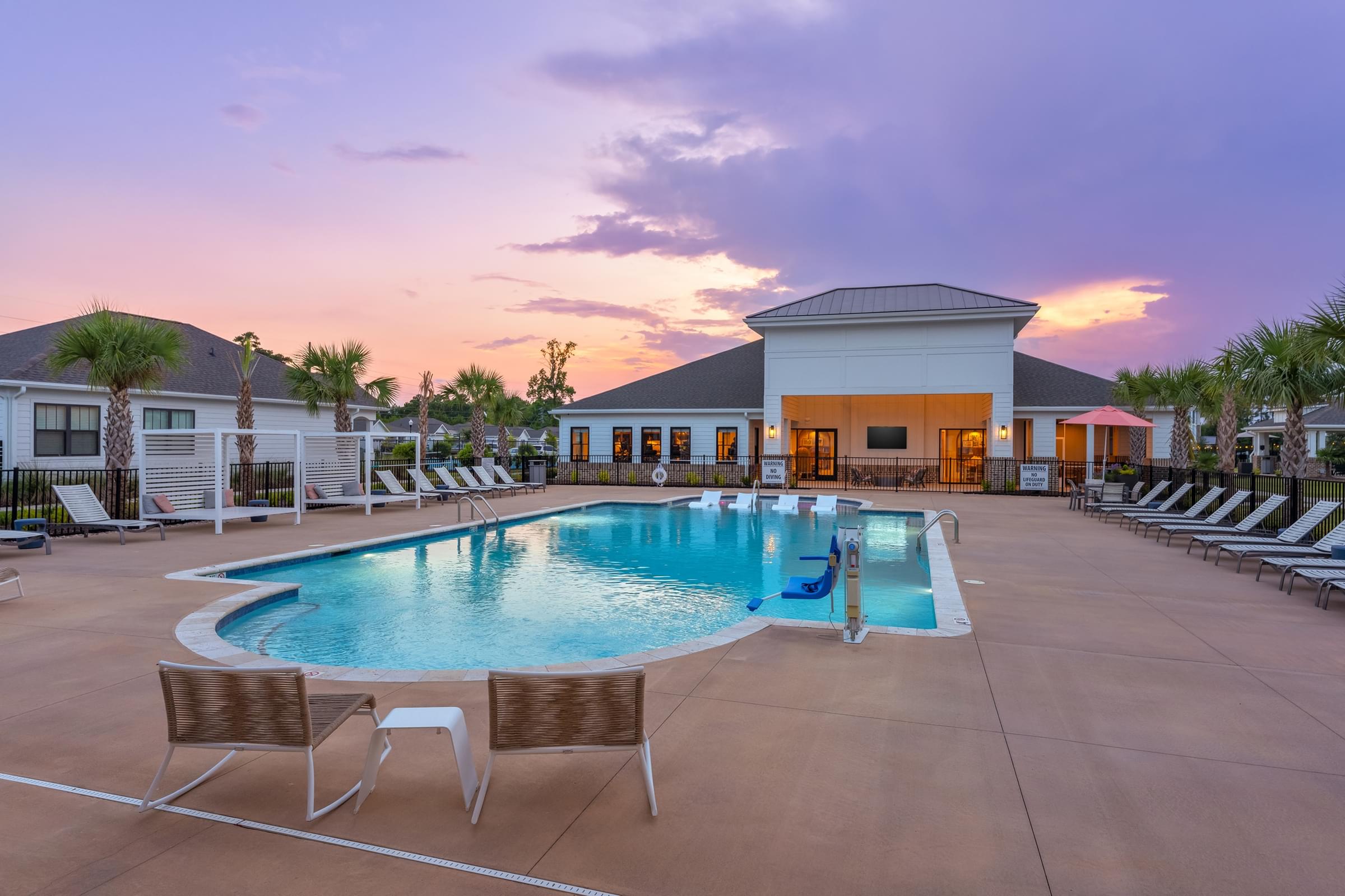 A pool with chairs around it and a building in the background.