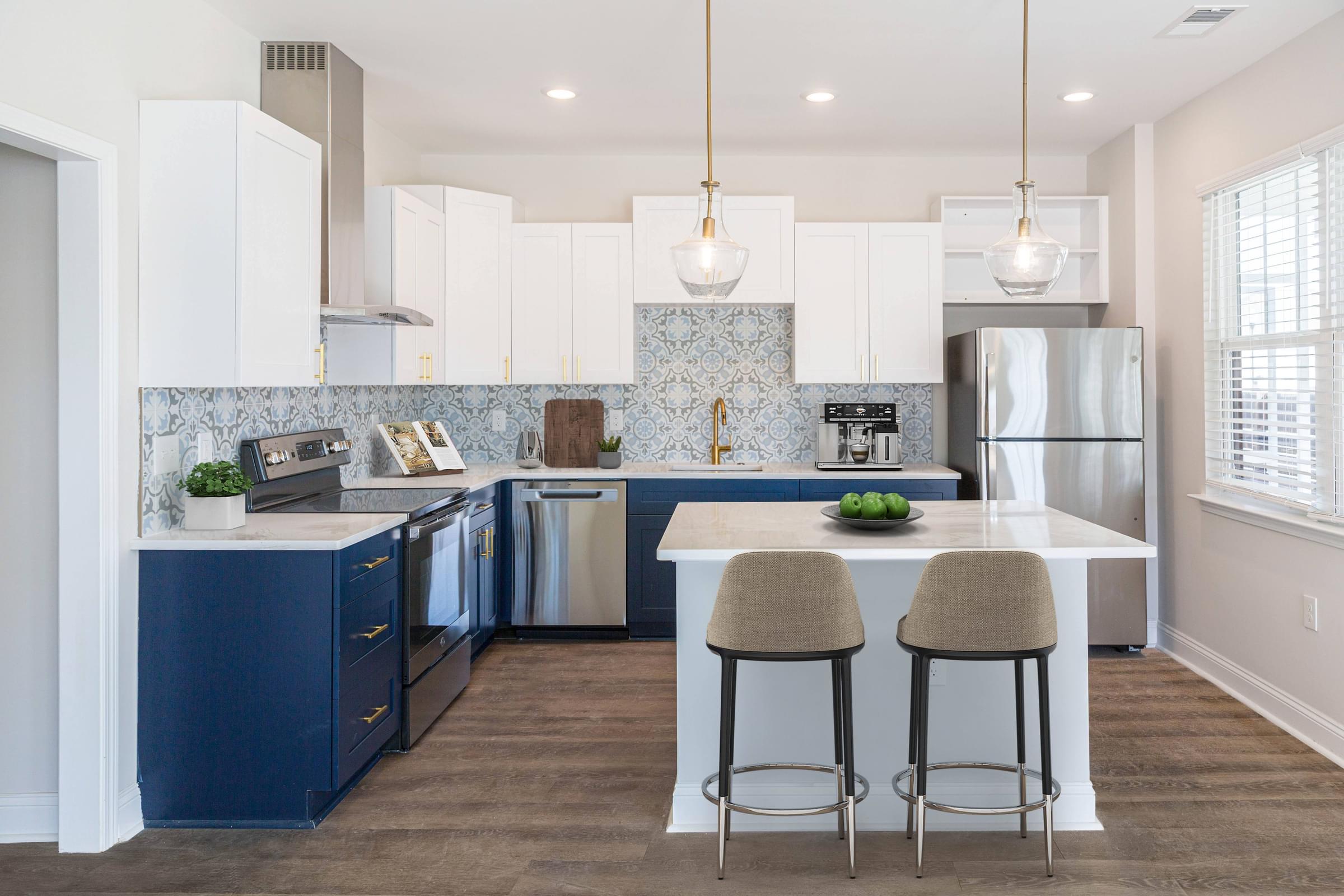 a white kitchen with blue cabinets and a white island with two stools