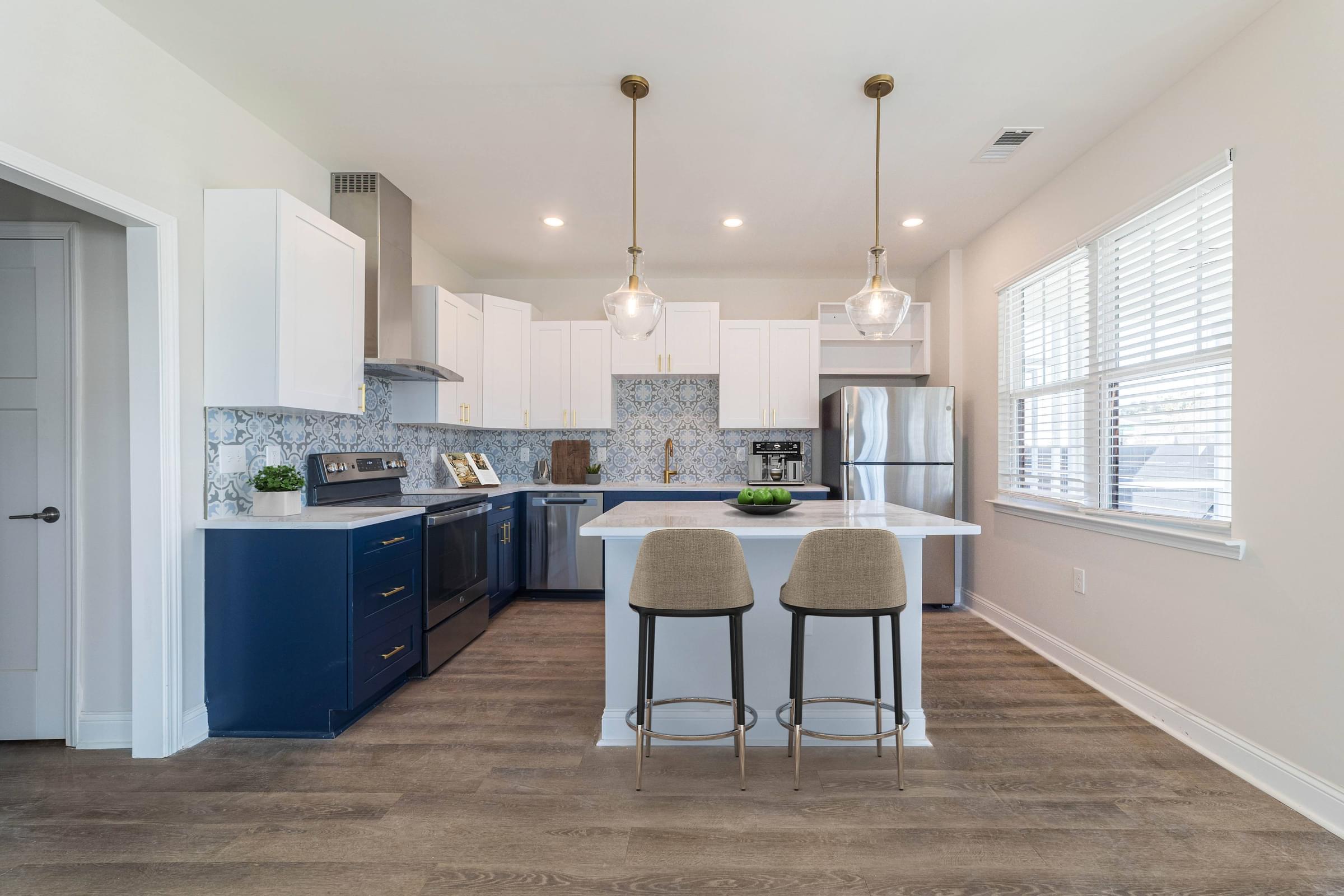 a kitchen with blue and white cabinets and a white island with two stools