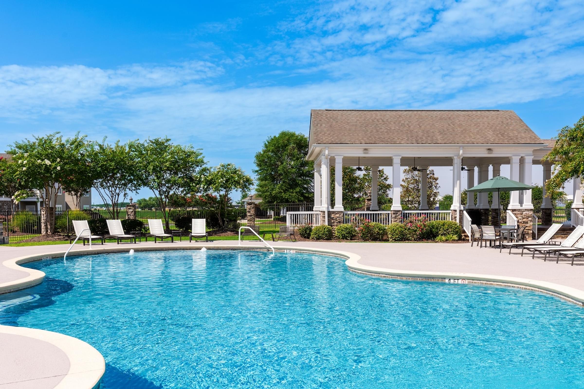 a large swimming pool in front of a mansion with a pool house