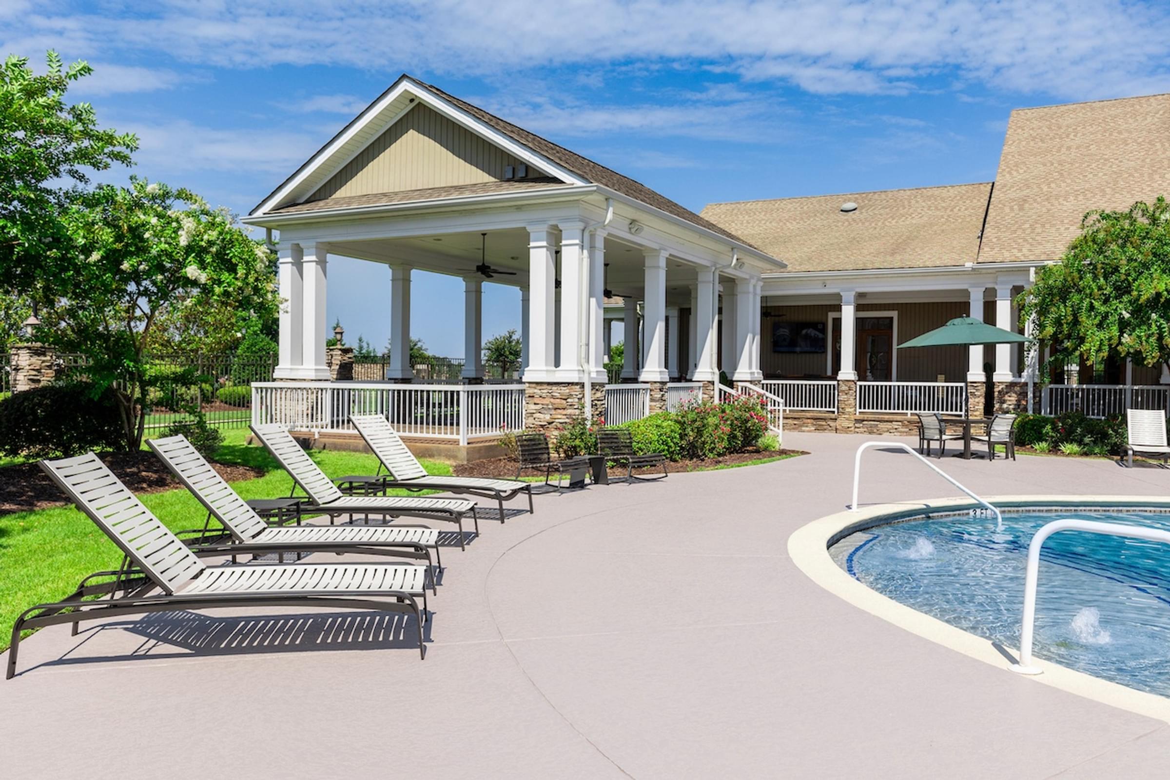 A pool area with sun loungers and a building with columns