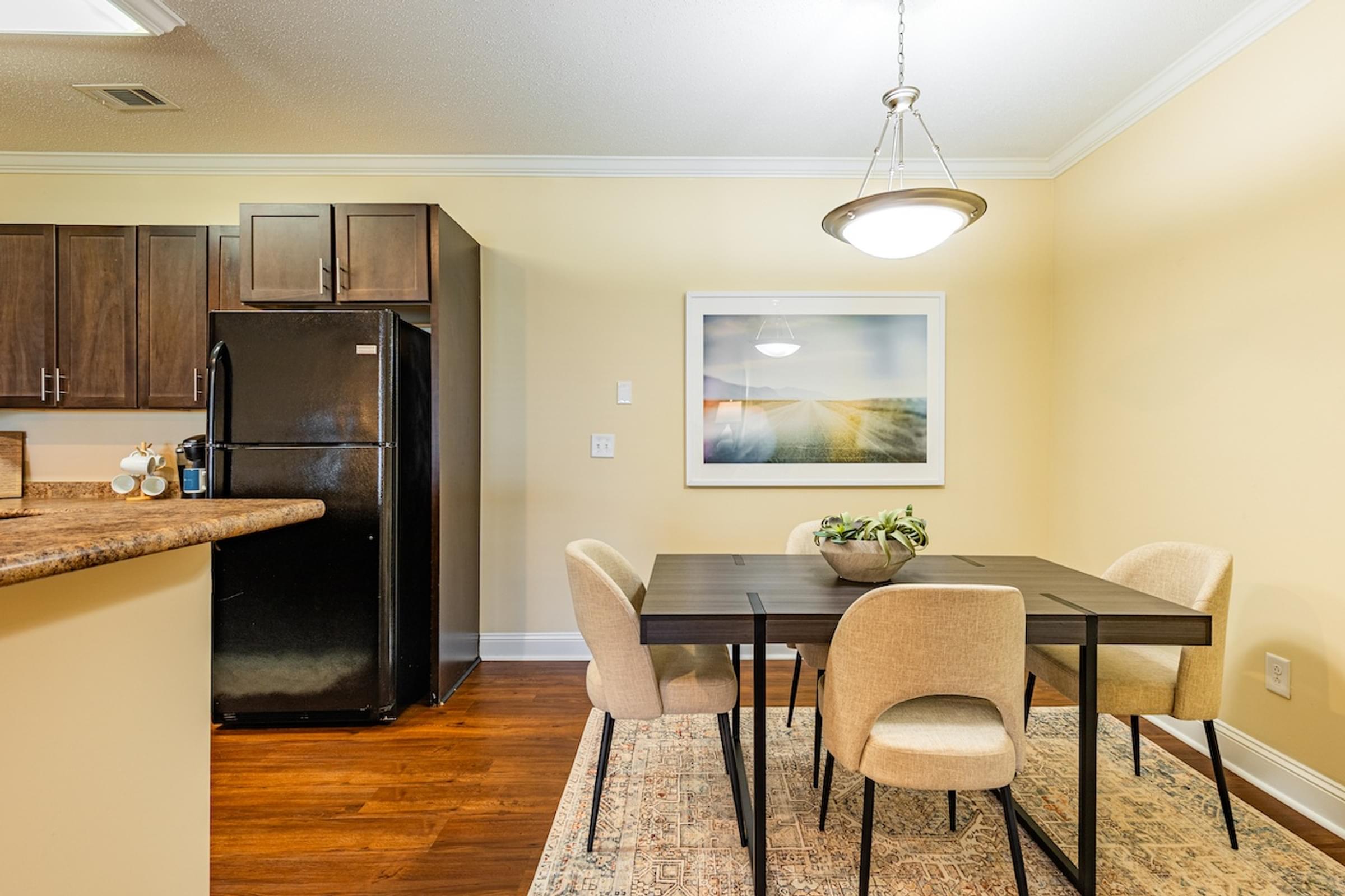 a dining room with a table and chairs and a kitchen with a refrigerator