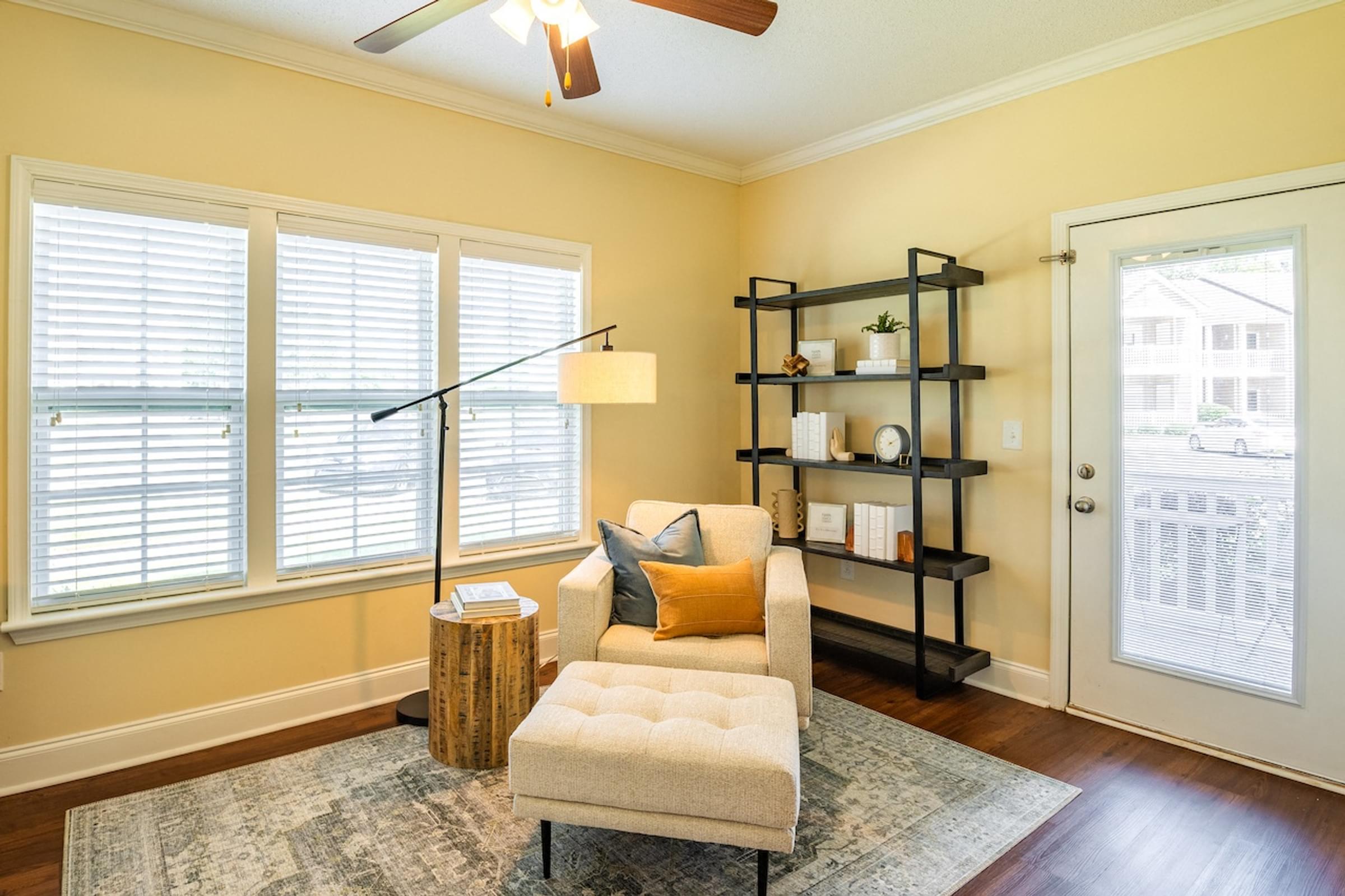 a living room with a chair and a ottoman in front of a window