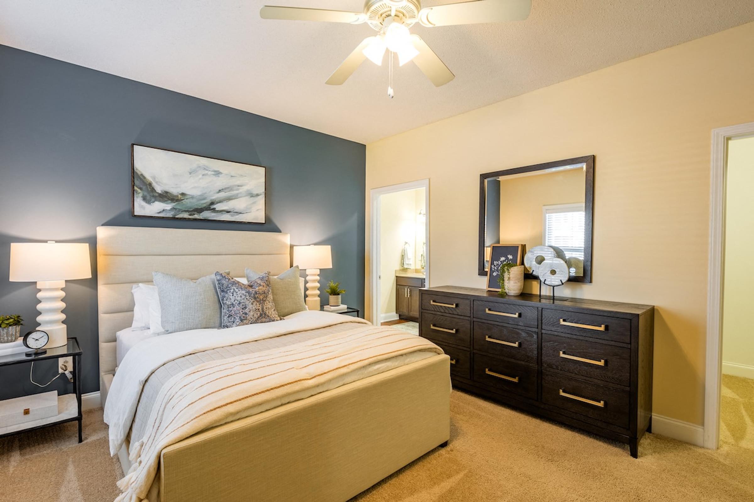 a bedroom with a bed and a dresser and a ceiling fan
