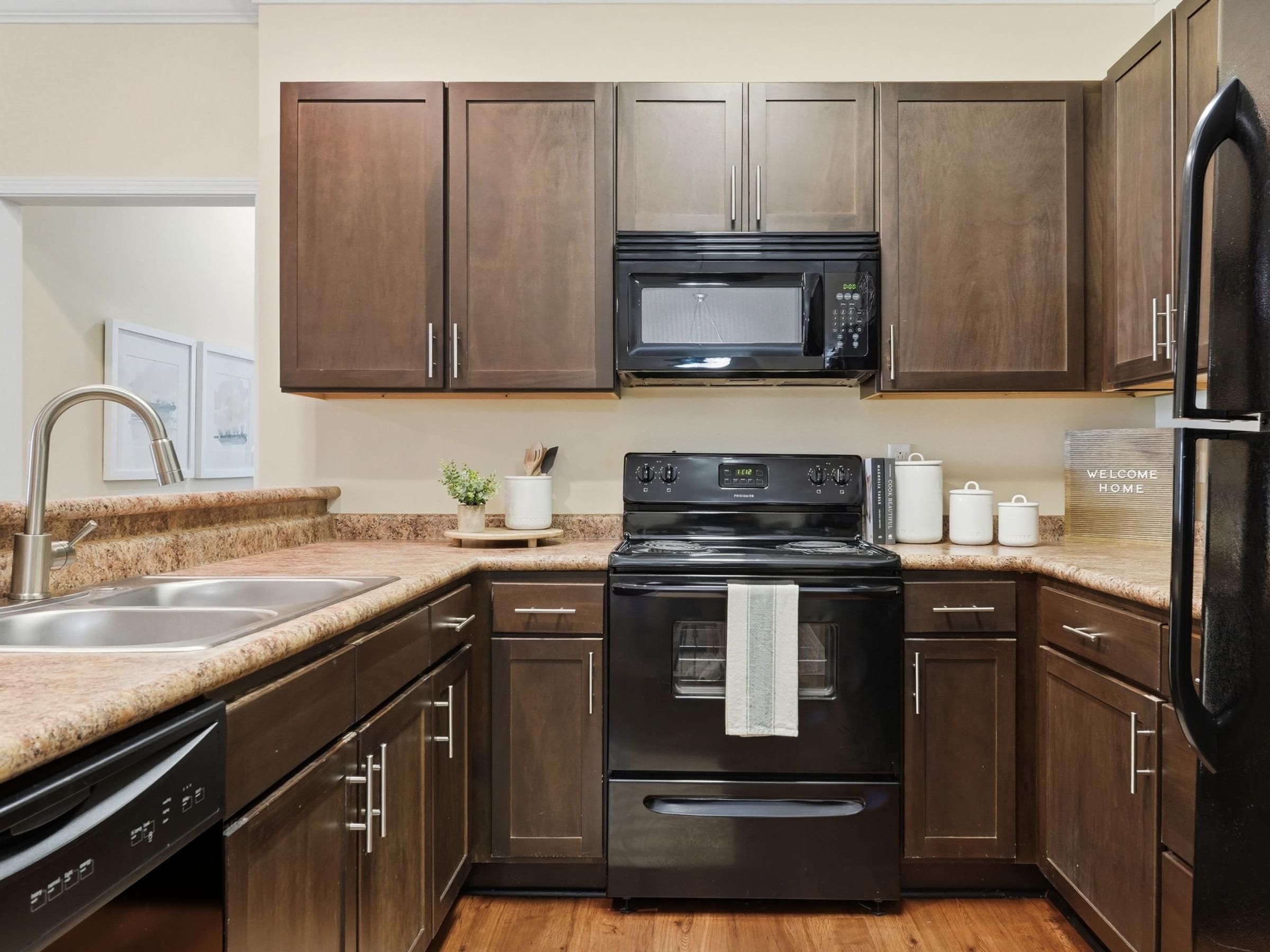 A kitchen with brown cabinets and black appliances.