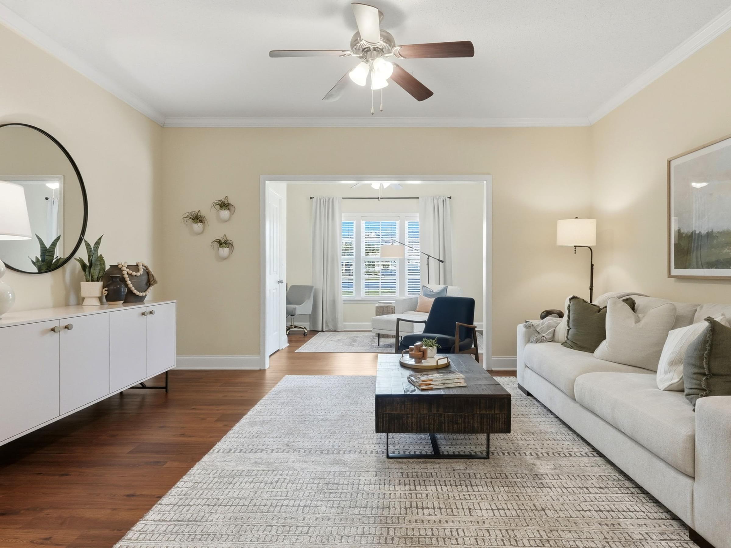 A living room with a white couch, a coffee table, and a ceiling fan.