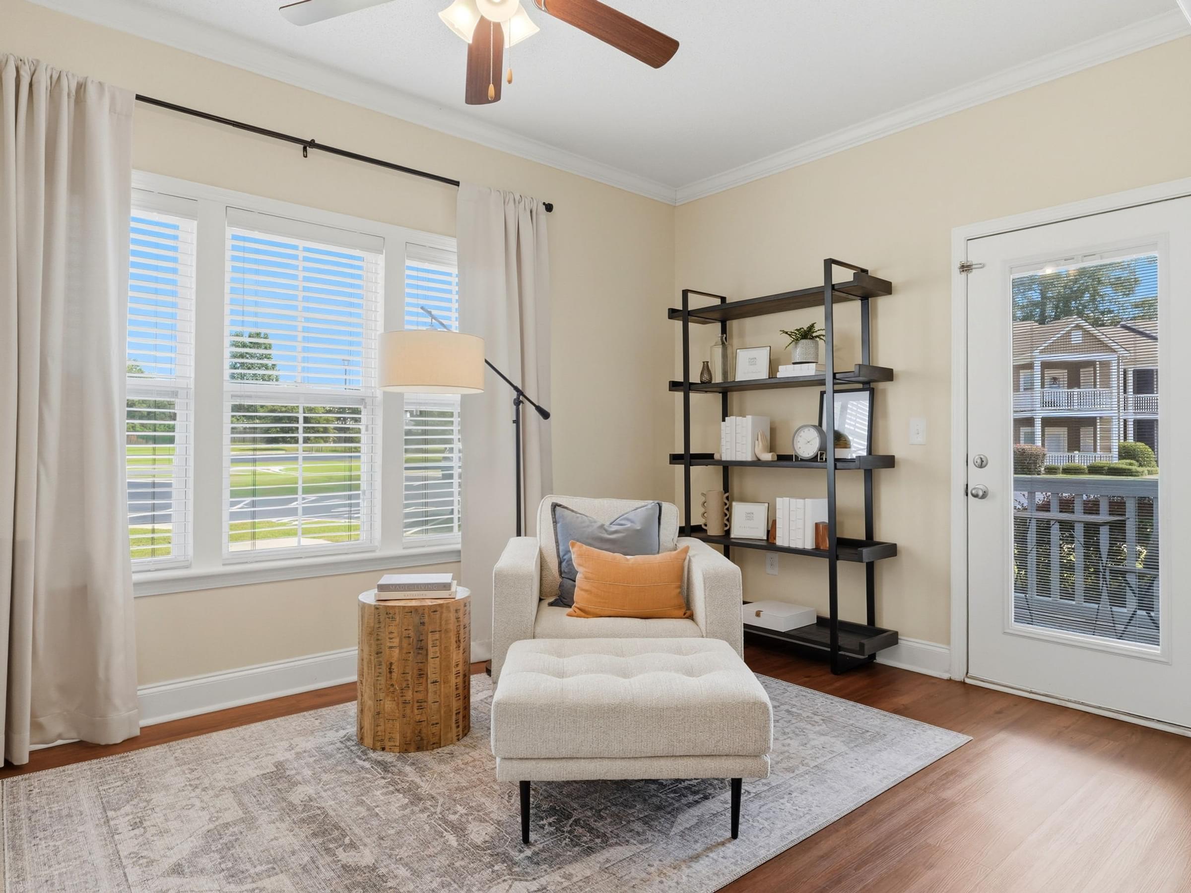 A living room with a chair, a table, and a fan.