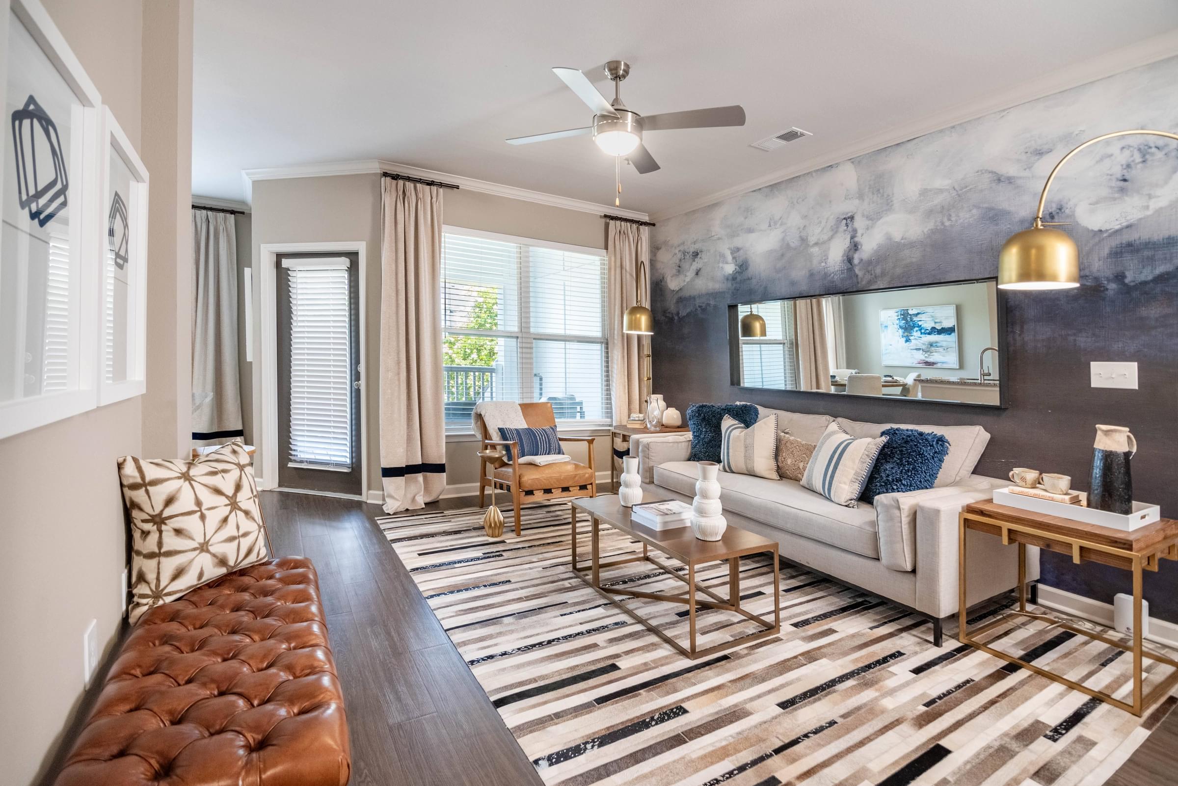 a living room with a couch and chairs and a ceiling fan