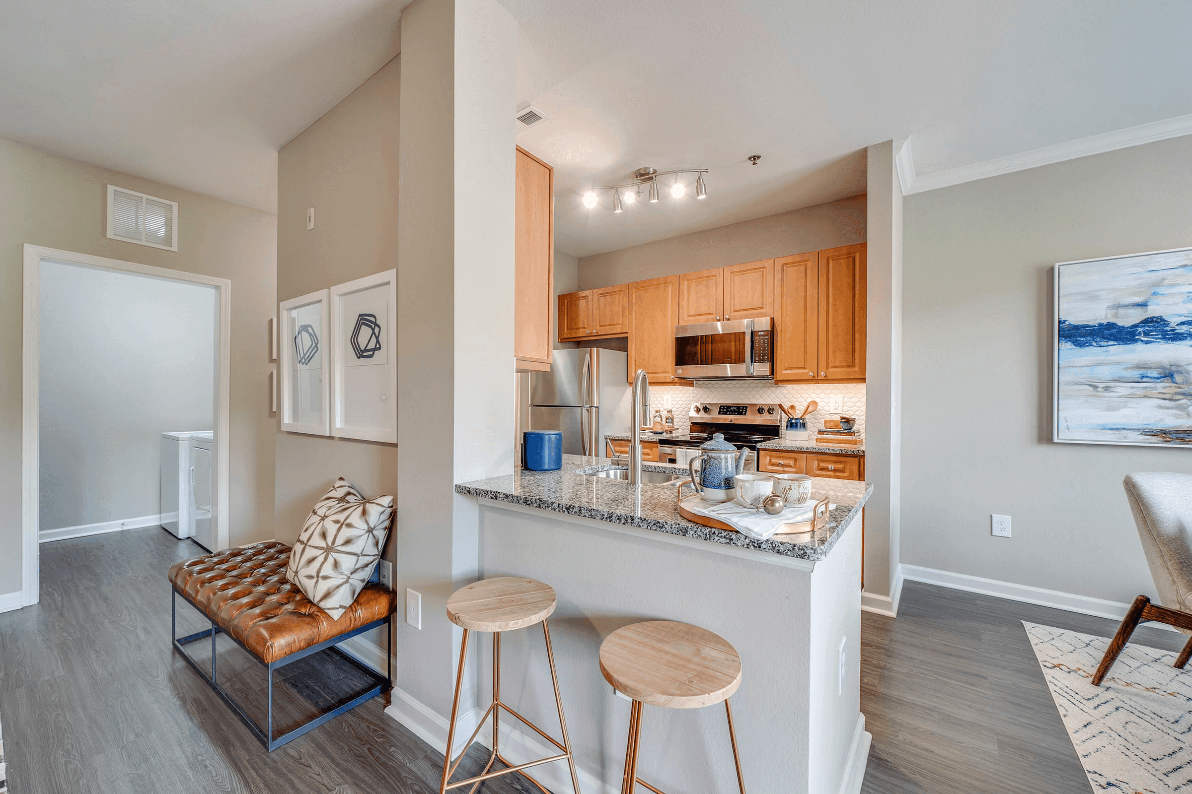 a kitchen with a bar and stools next to a living room with a counter