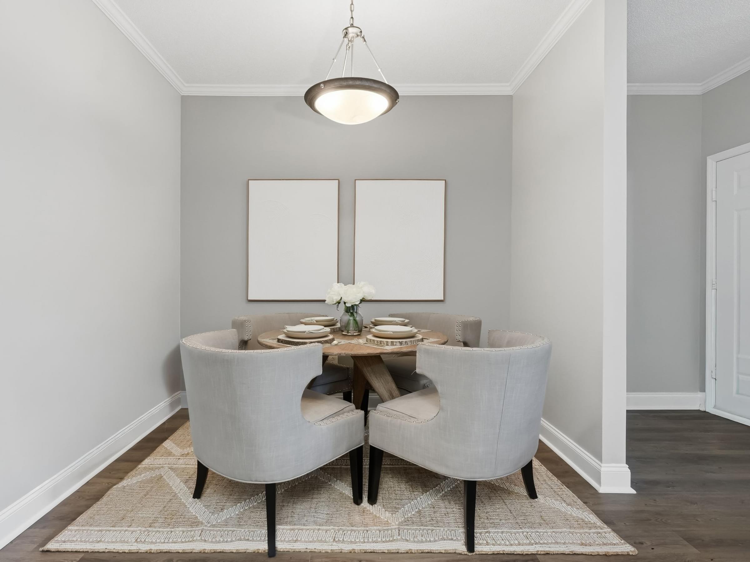A dining room with a table set for two and two grey chairs.