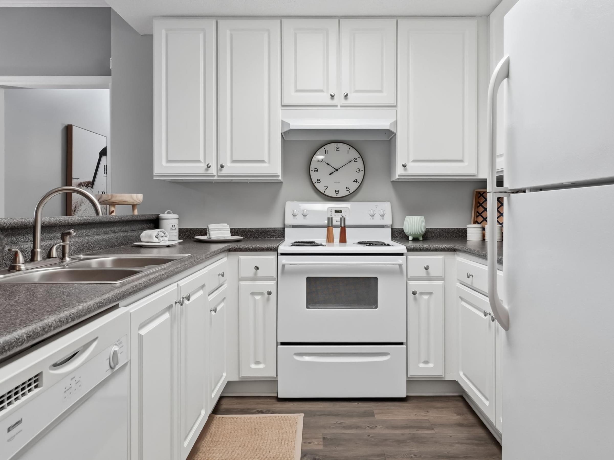 A white kitchen with a clock on the wall.