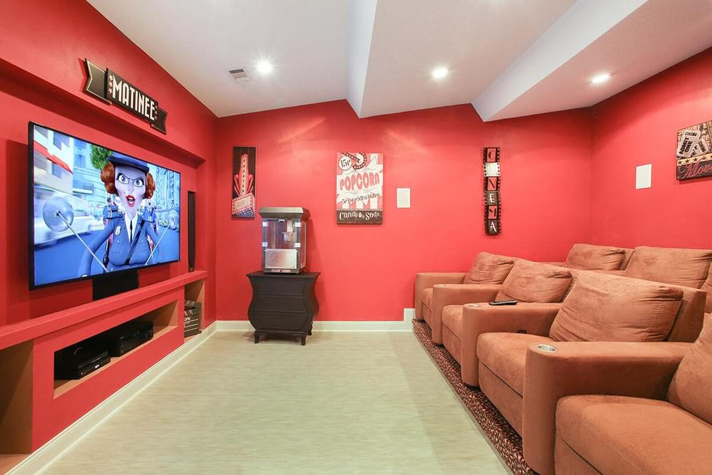 a home theater with red walls and couches