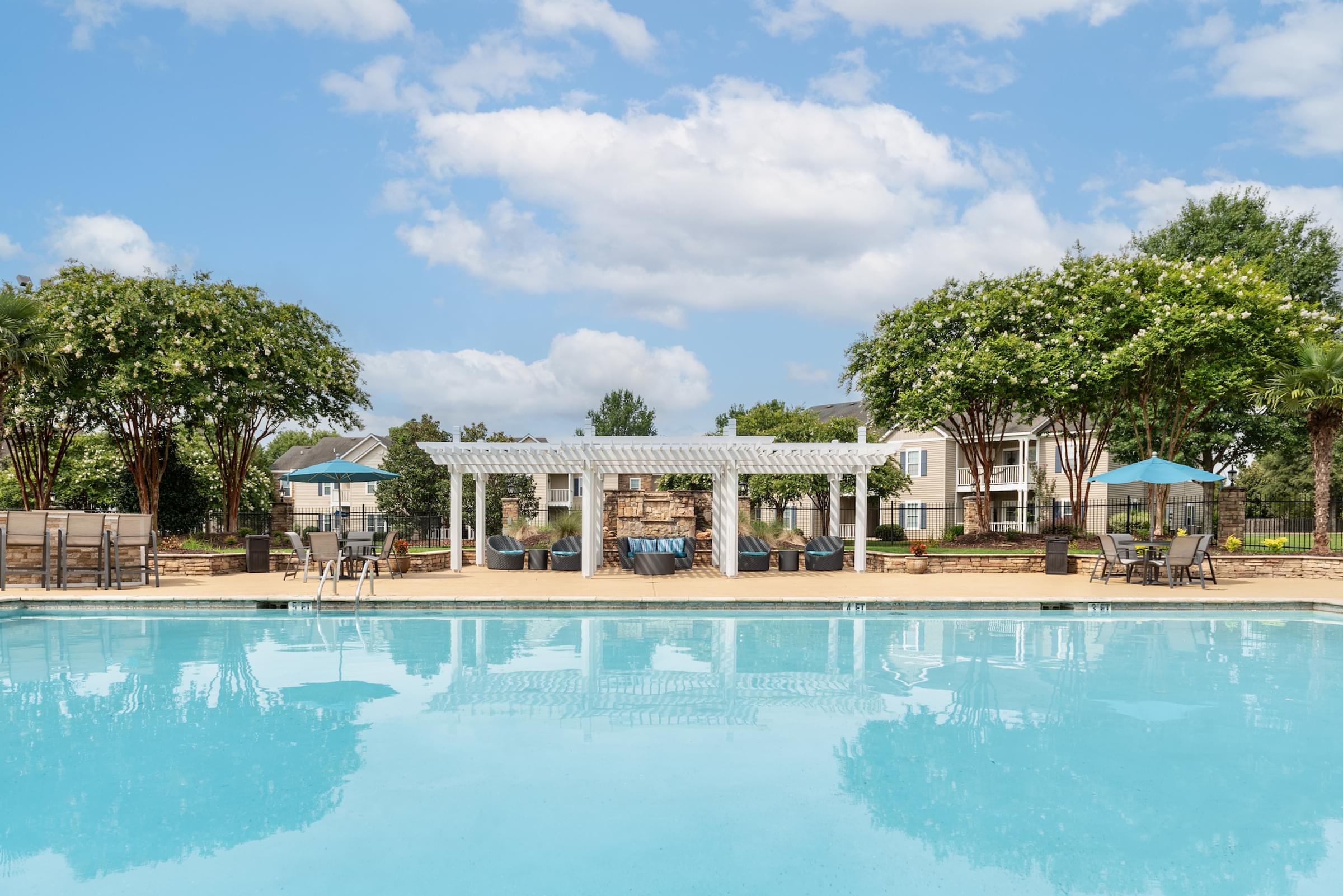 a swimming pool with chairs and a pergola next to a resort pool