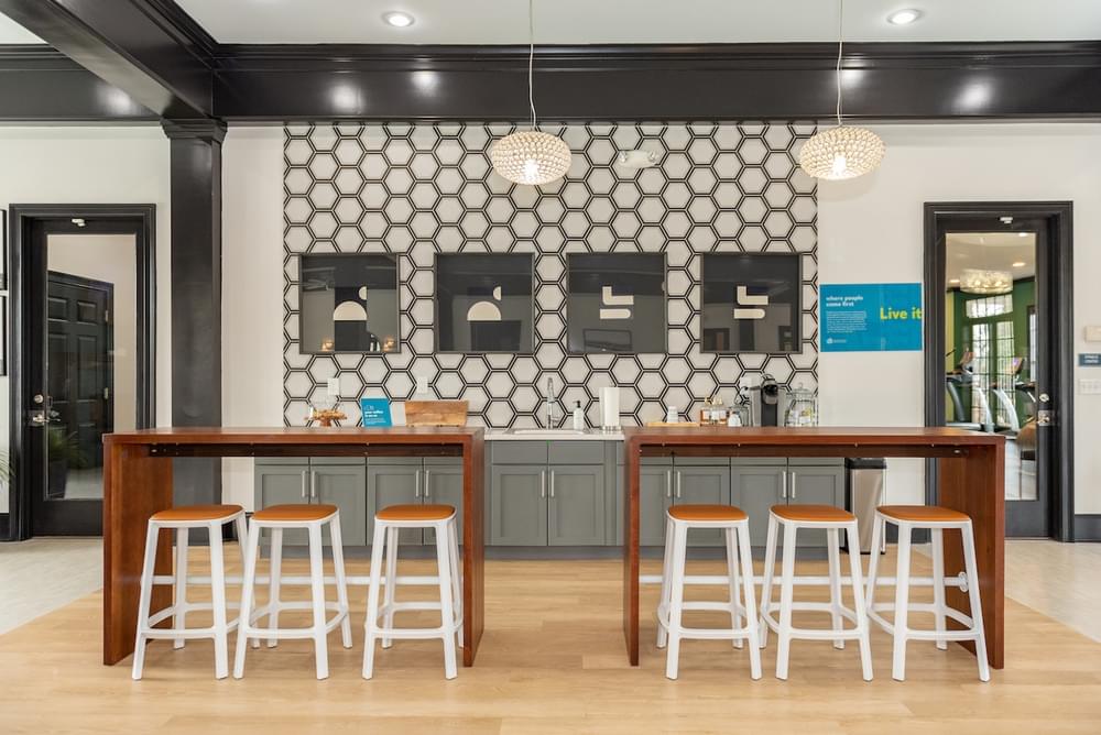 a restaurant with a bar and stools in front of a white and black wall