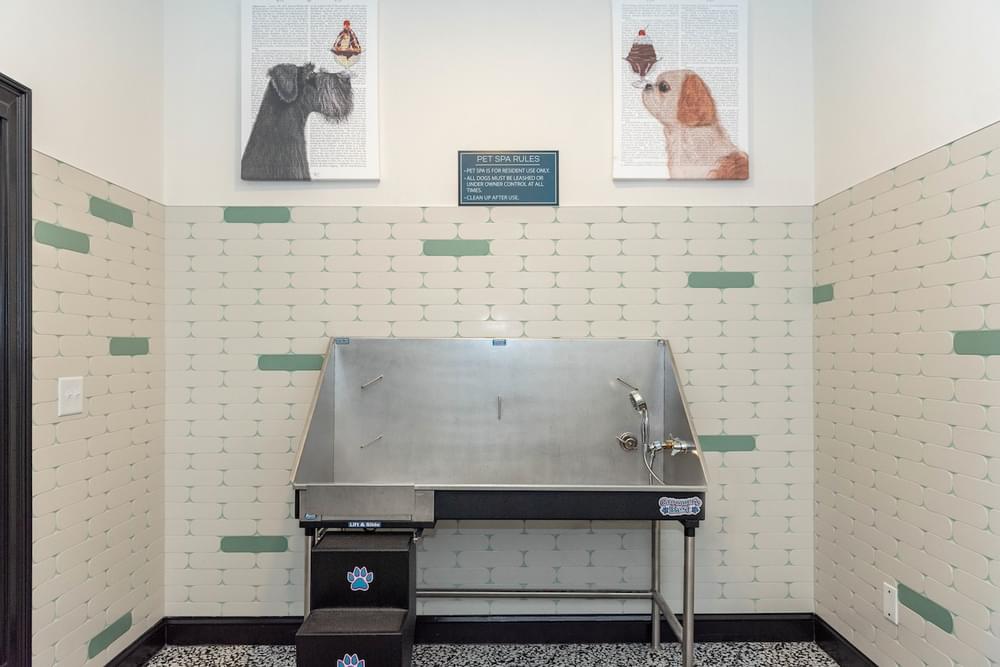 a large metal sink in a room with green and white tiled walls
