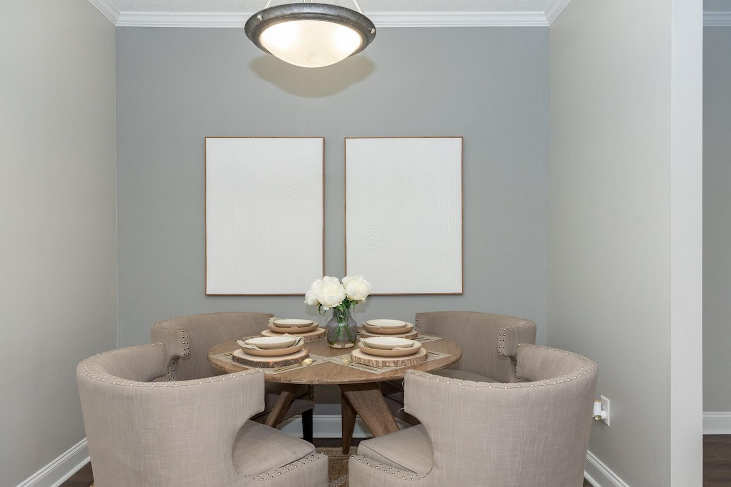 a dining room with a table and chairs and two paintings on the wall