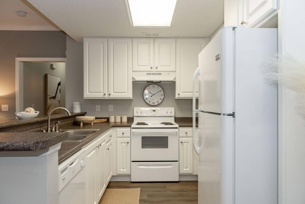 a kitchen with white cabinets and a clock on the wall