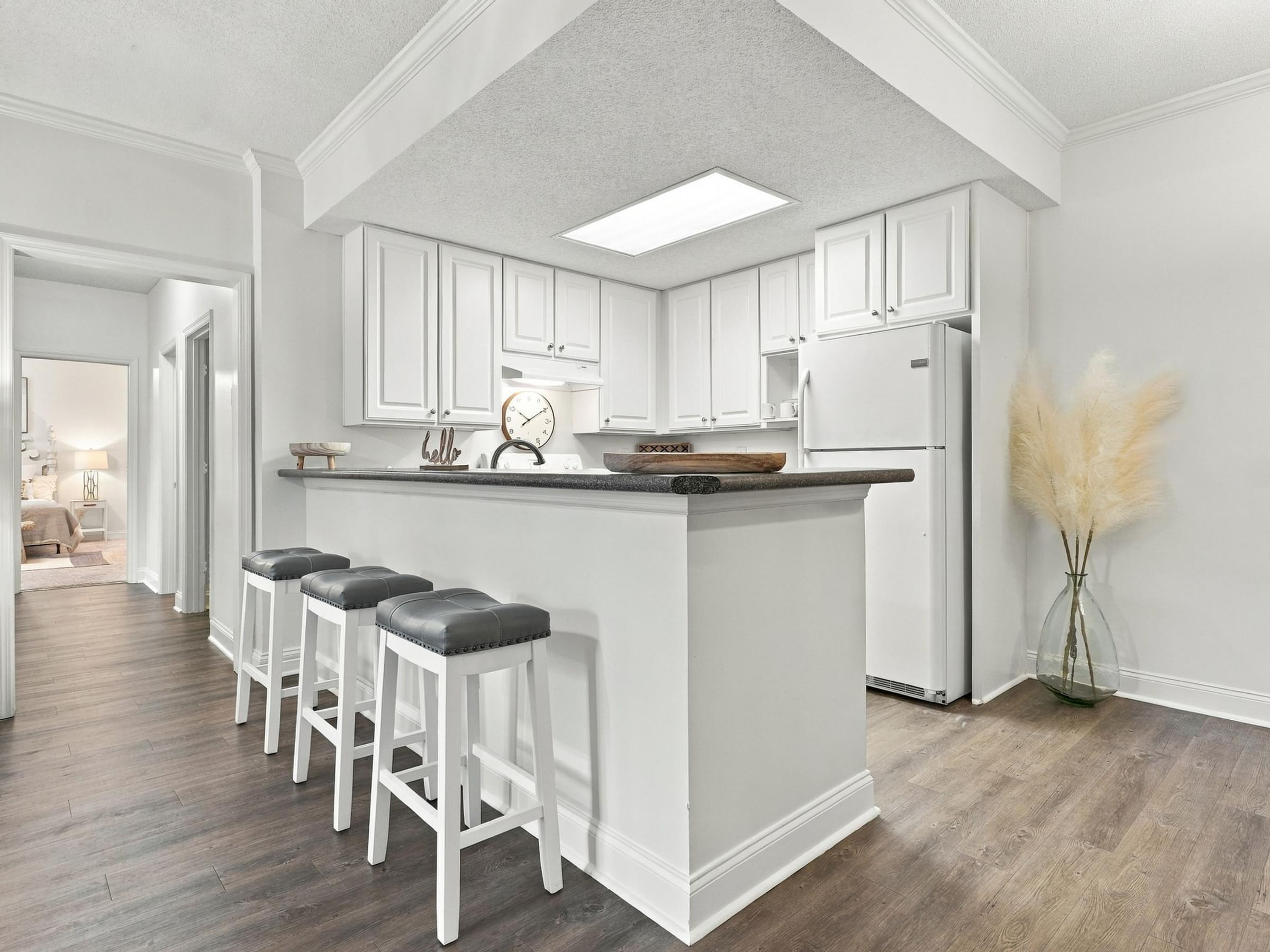 A kitchen with white cabinets and a white fridge.