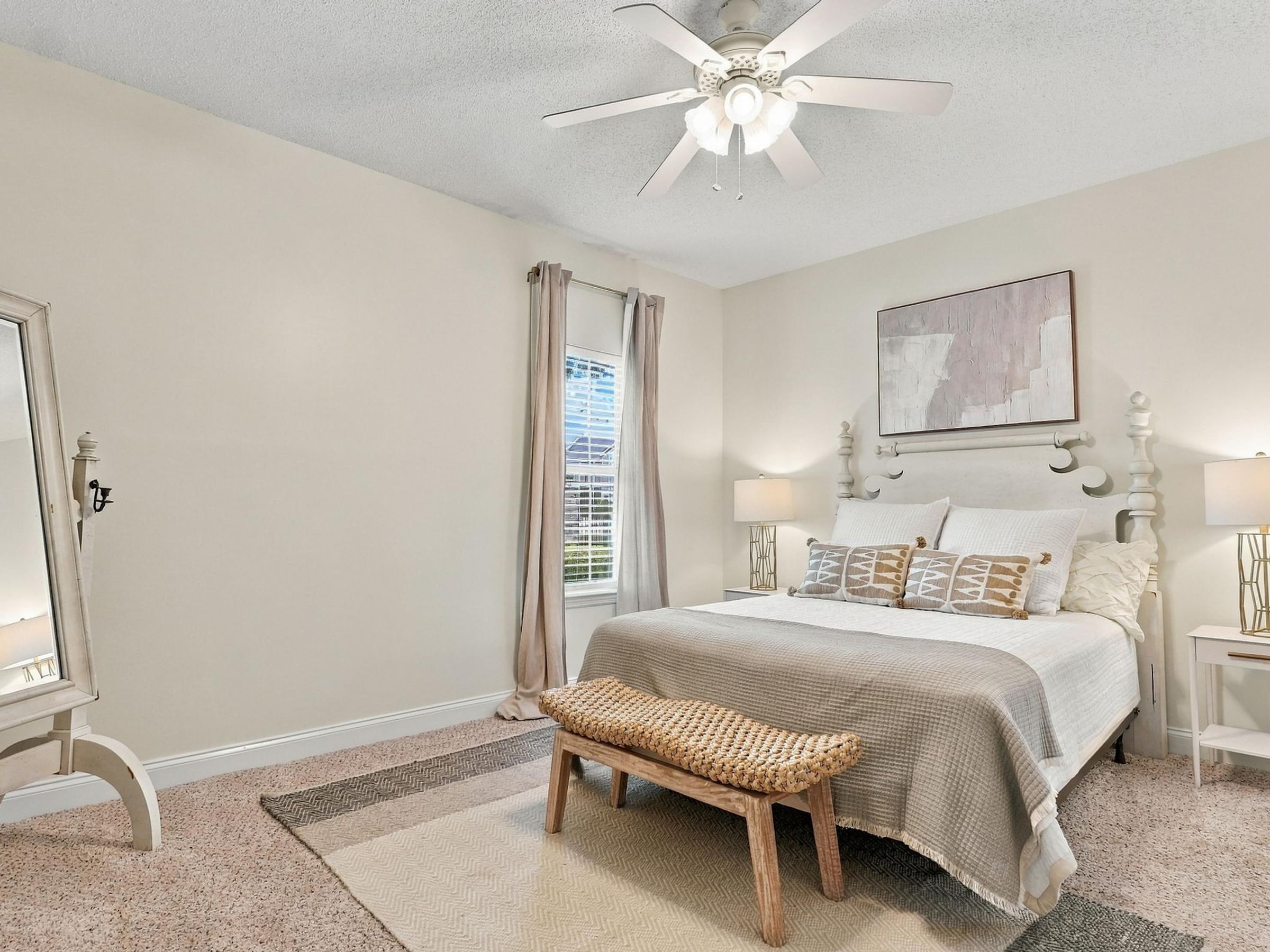 A bedroom with a bed, a bench, and a ceiling fan.