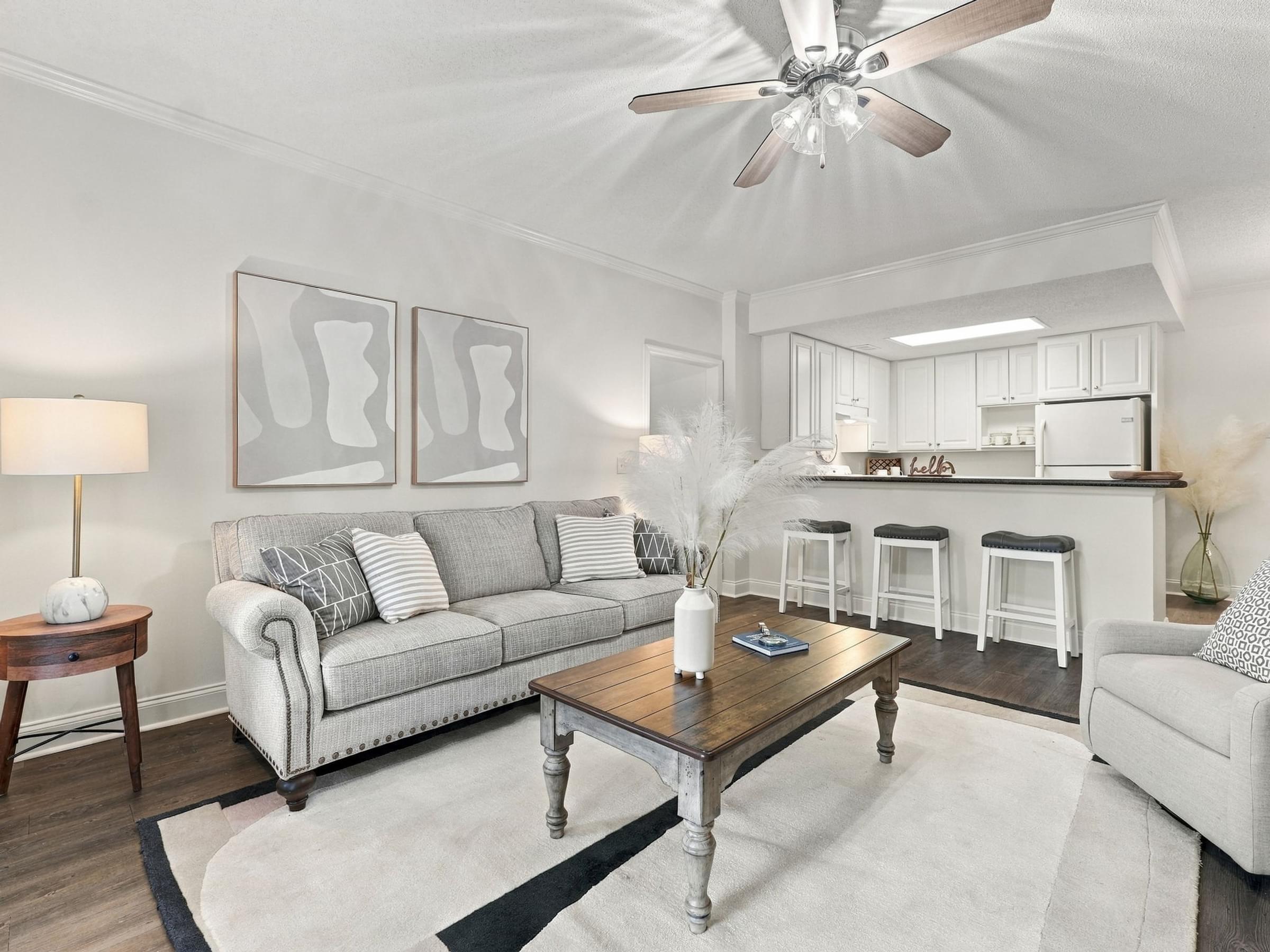 A living room with a grey couch, a coffee table, and a ceiling fan.