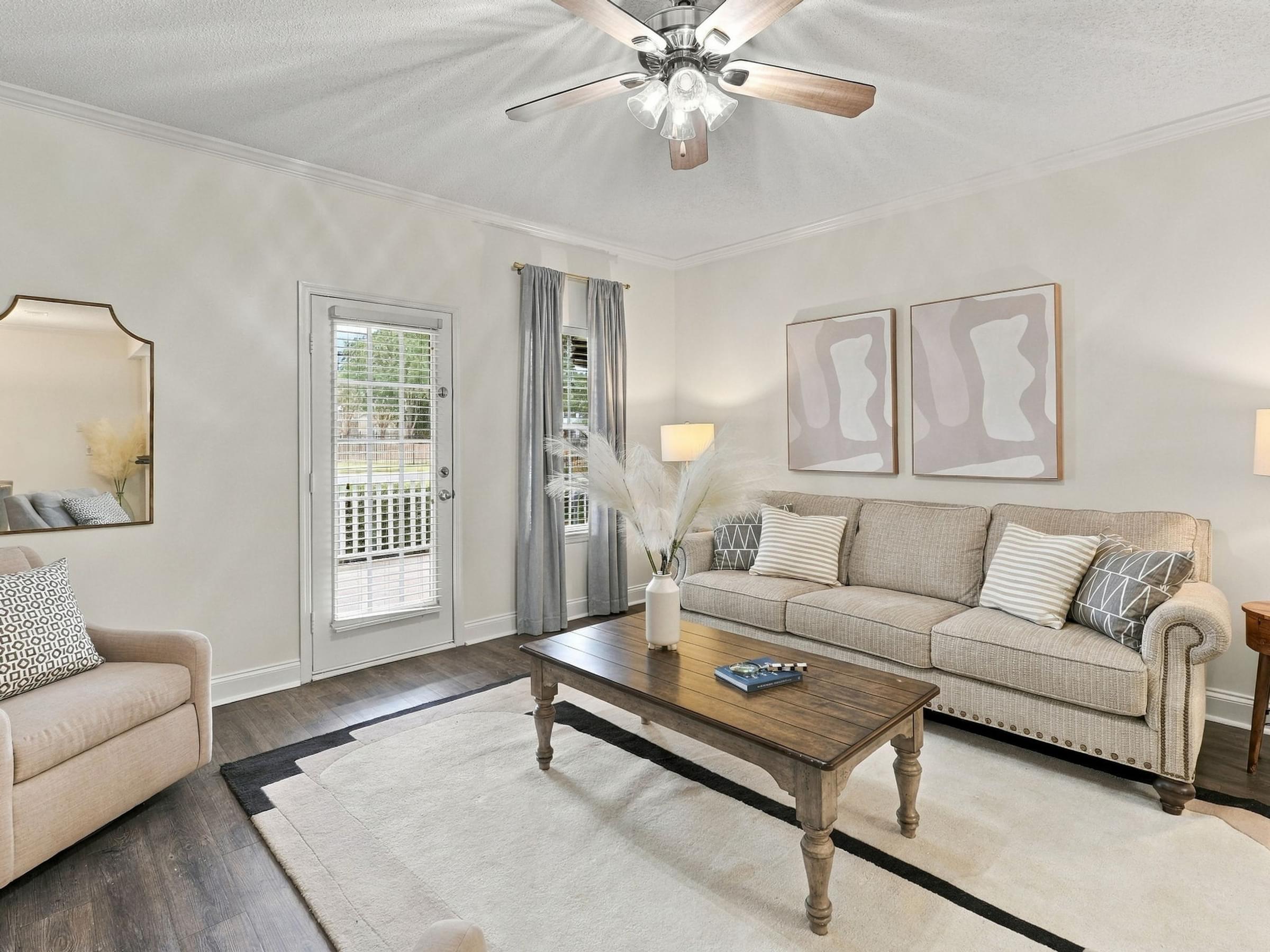 A living room with a couch, coffee table, and a ceiling fan.