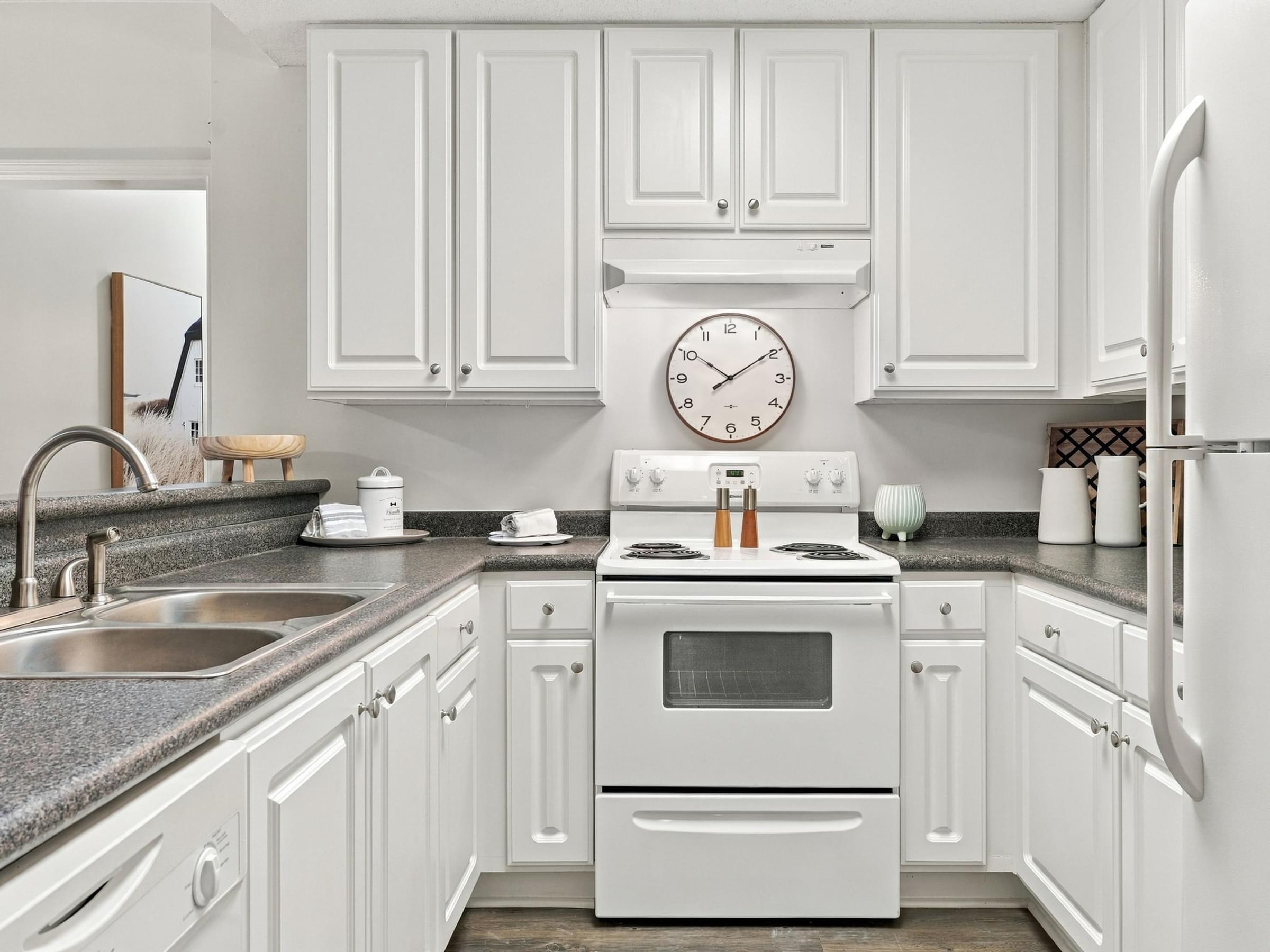 A white kitchen with a clock on the wall.