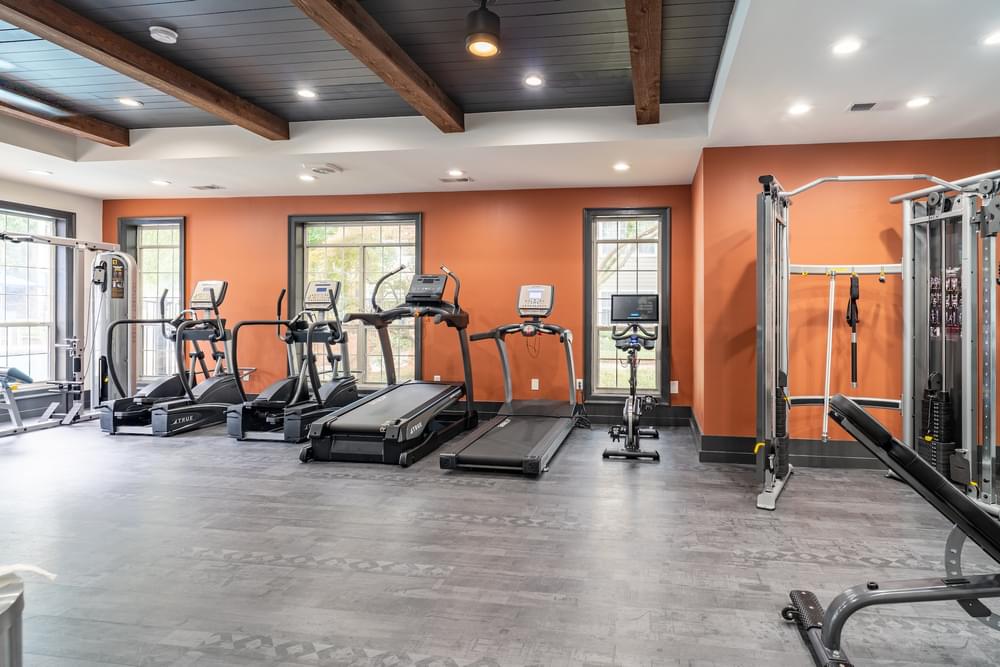 a gym with cardio machines and weights on the floor and windows