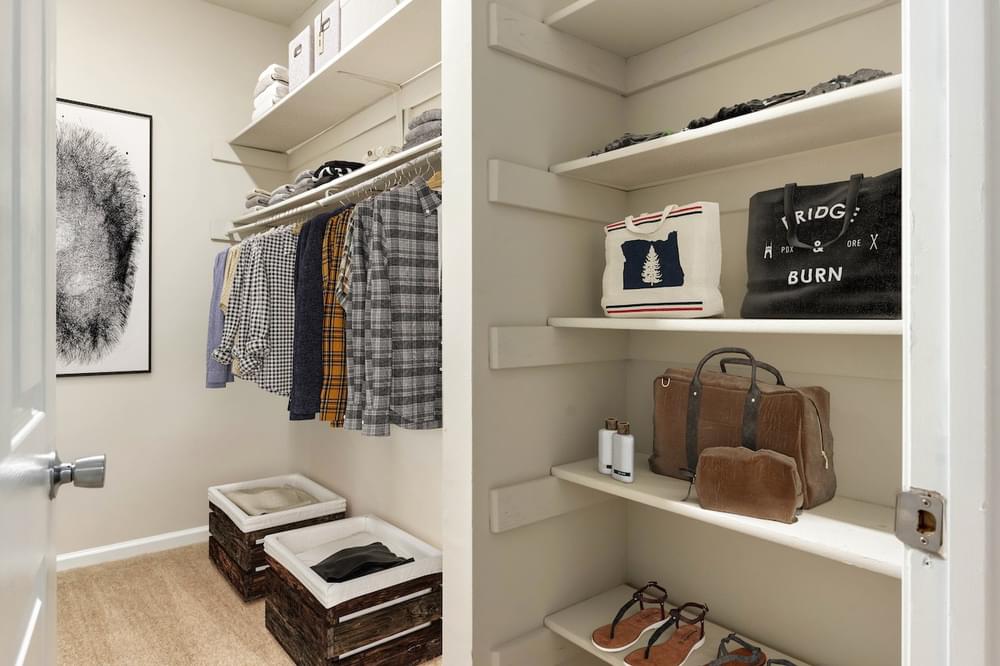 a walk in closet with white shelves and a white door