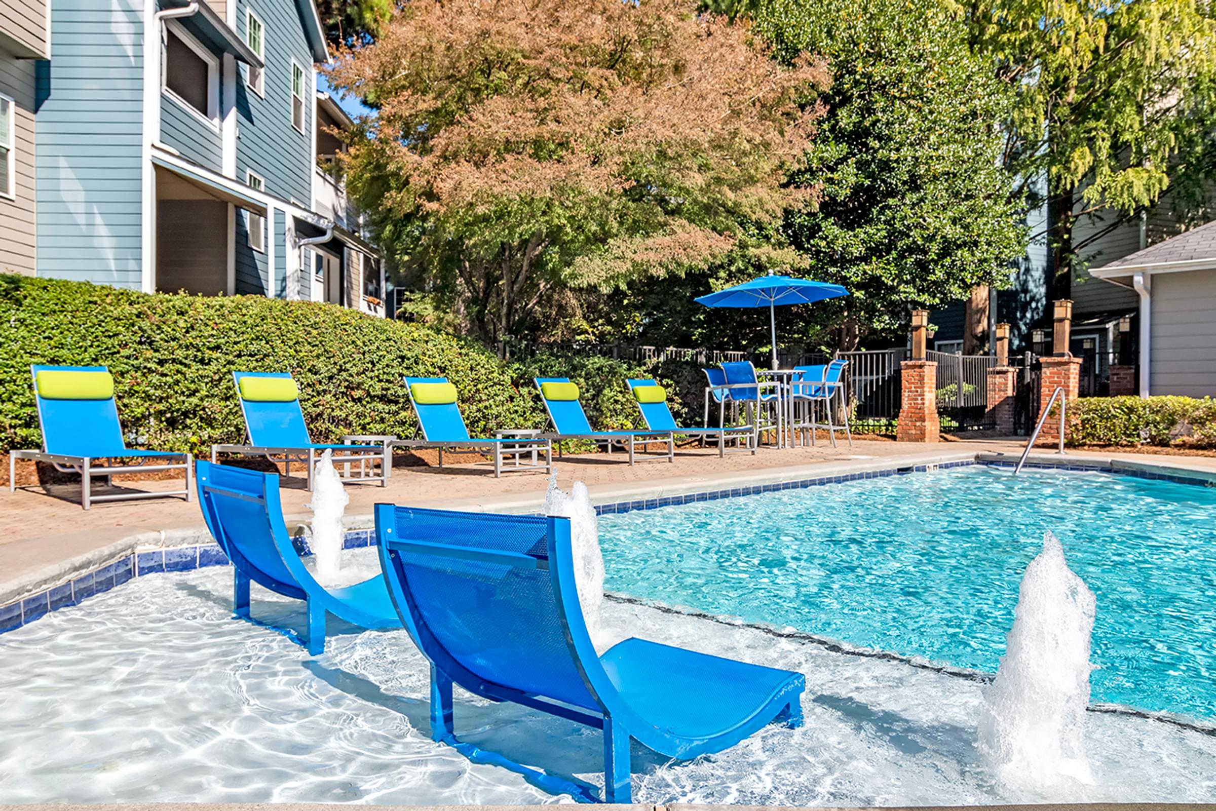 a swimming pool with blue chairs next to a house