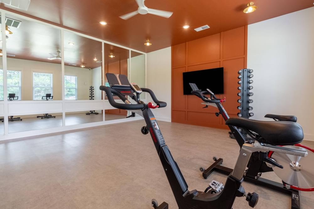 a gym with exercise equipment and a large screen tv