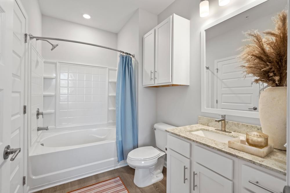 a bathroom with white cabinets and a blue shower curtain