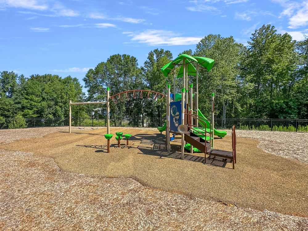 a playground with a swing set and sand and trees