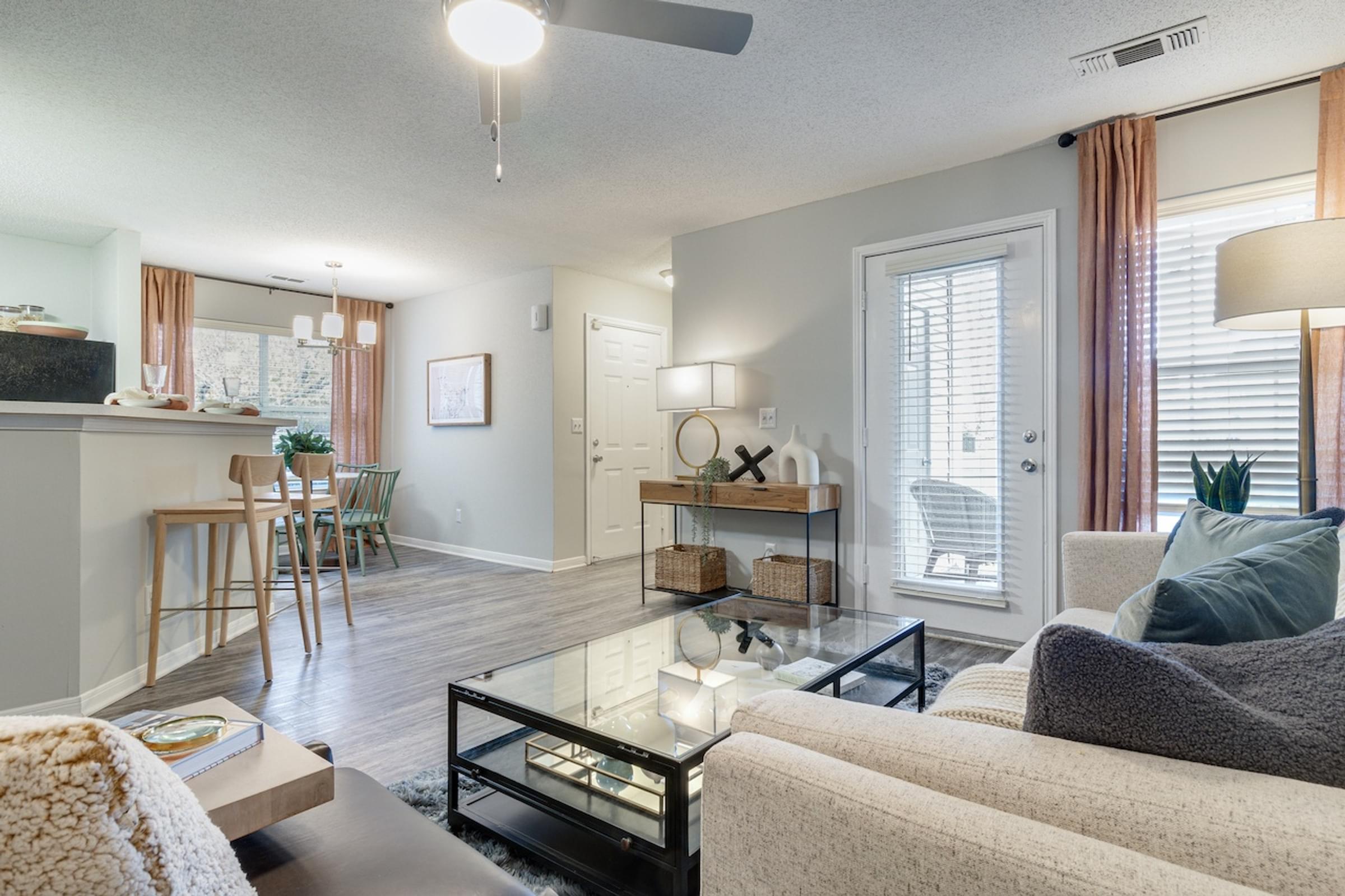 A open concept living room with a couch, coffee table, and a ceiling fan.