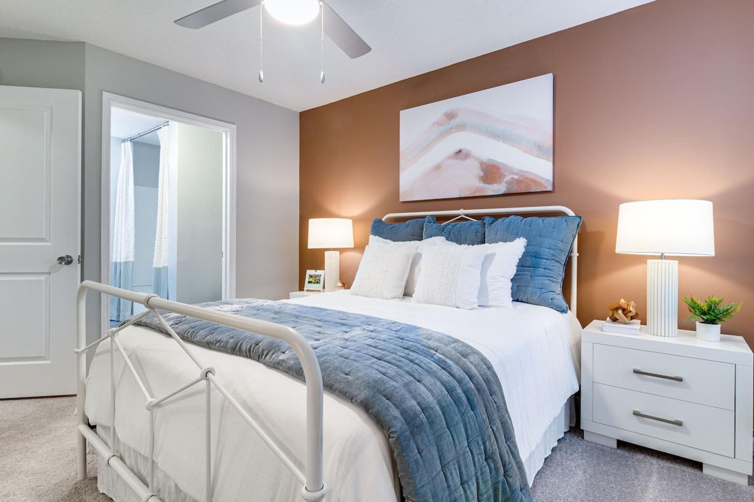 A bedroom with a white bed and a white nightstands