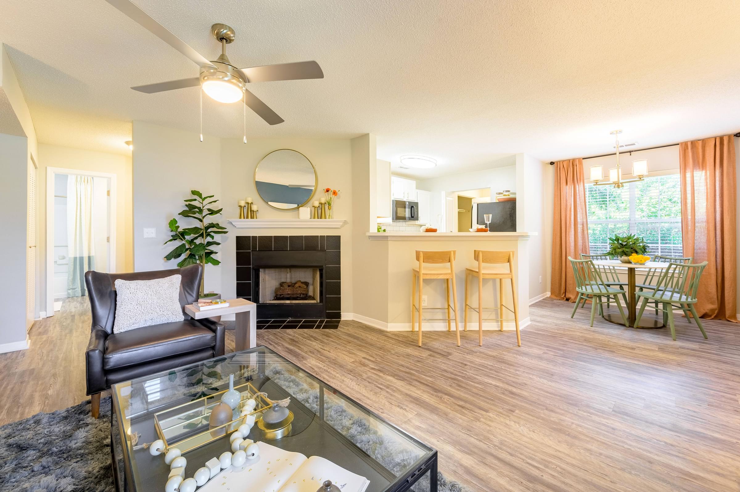 A living room with a fireplace, separate dining area, and bar with two bar stools