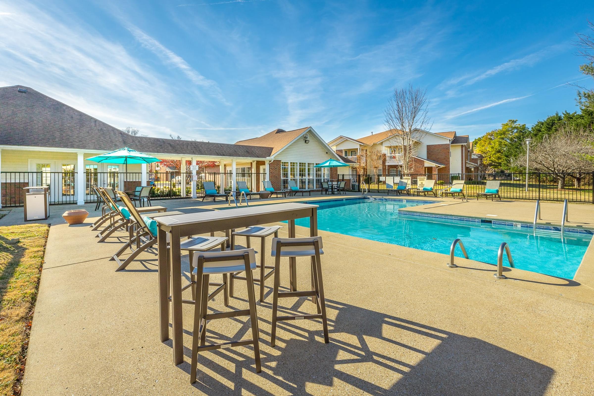 A poolside bar area with a long table and chairs.