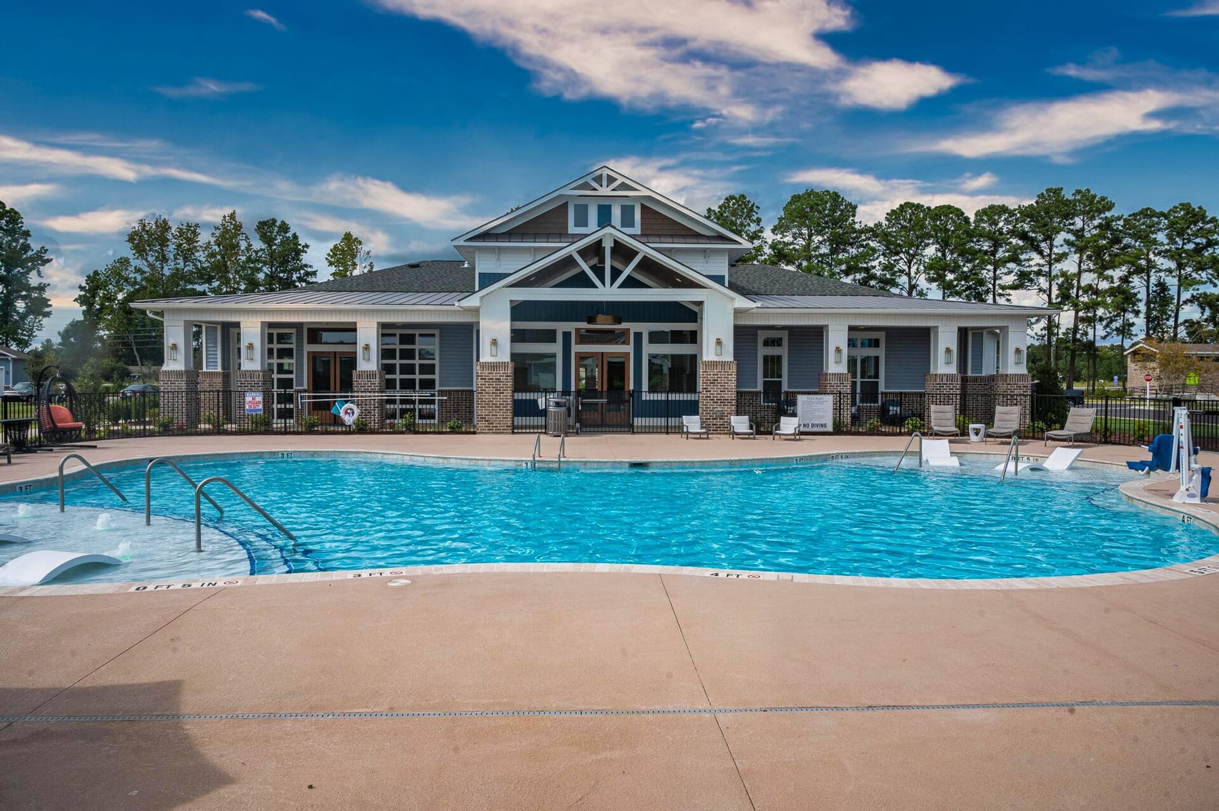 a swimming pool in front of a house with a resort style pool