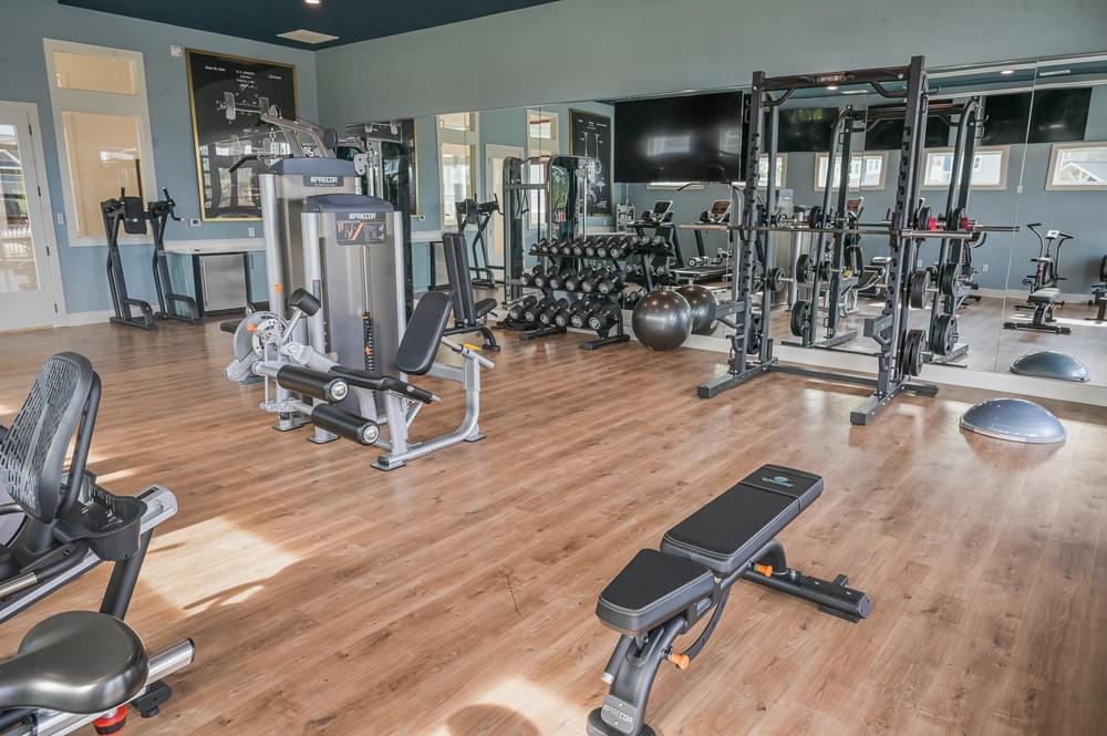 a gym with weights and cardio equipment on a wood floor