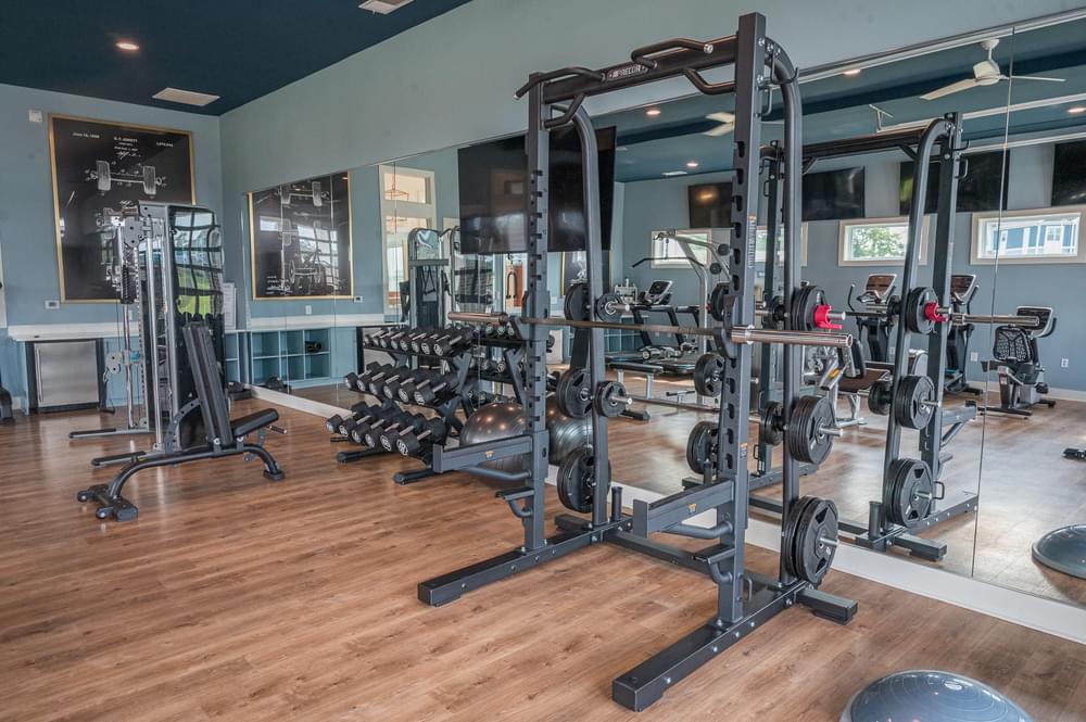 a gym with weights and cardio equipment on a wooden floor