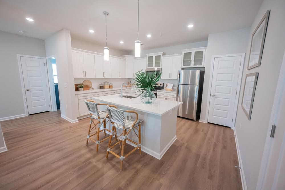 a kitchen with white cabinets and a white island with stools