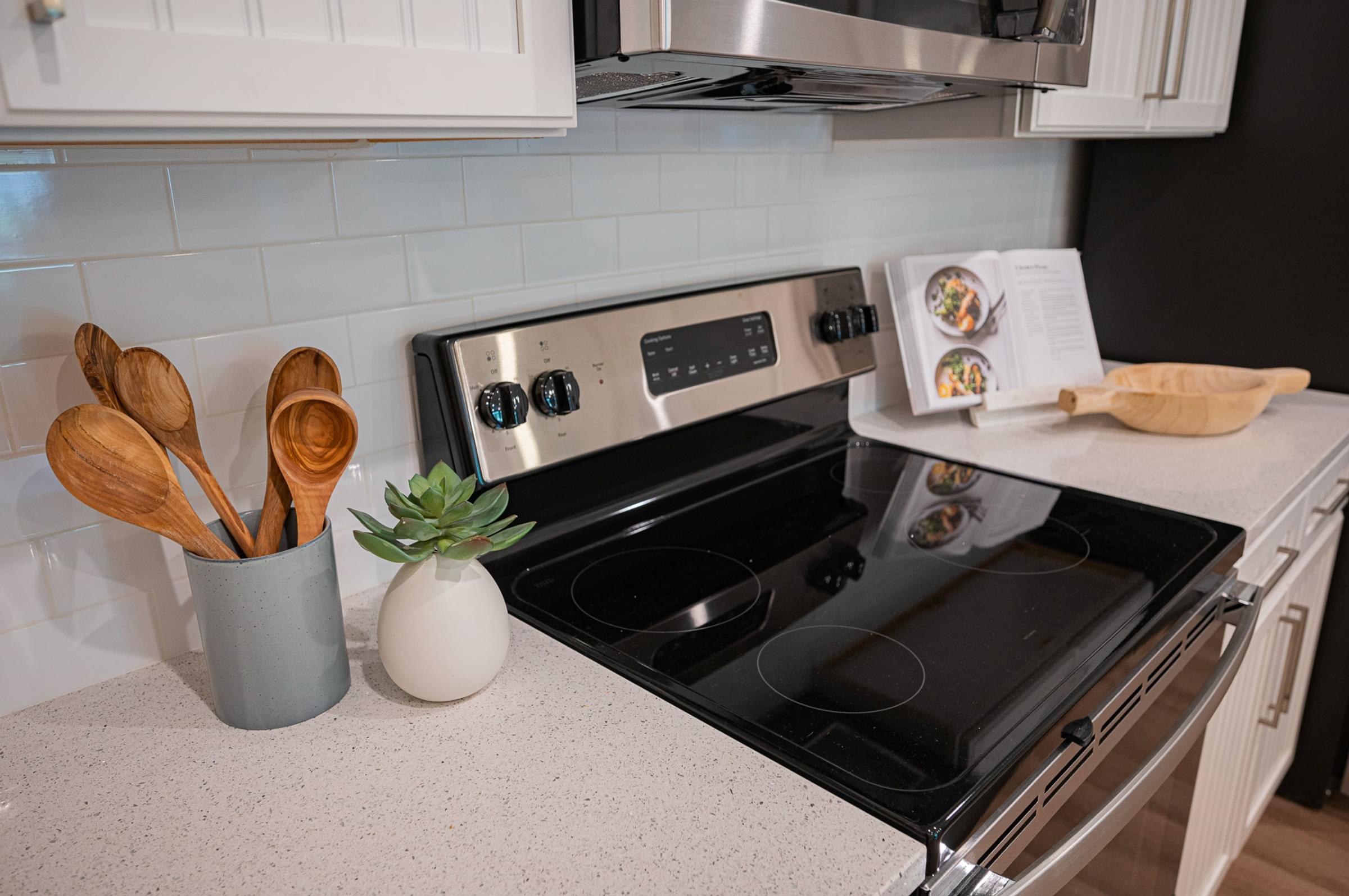 a kitchen with a stove and a counter top with spoons and a vase