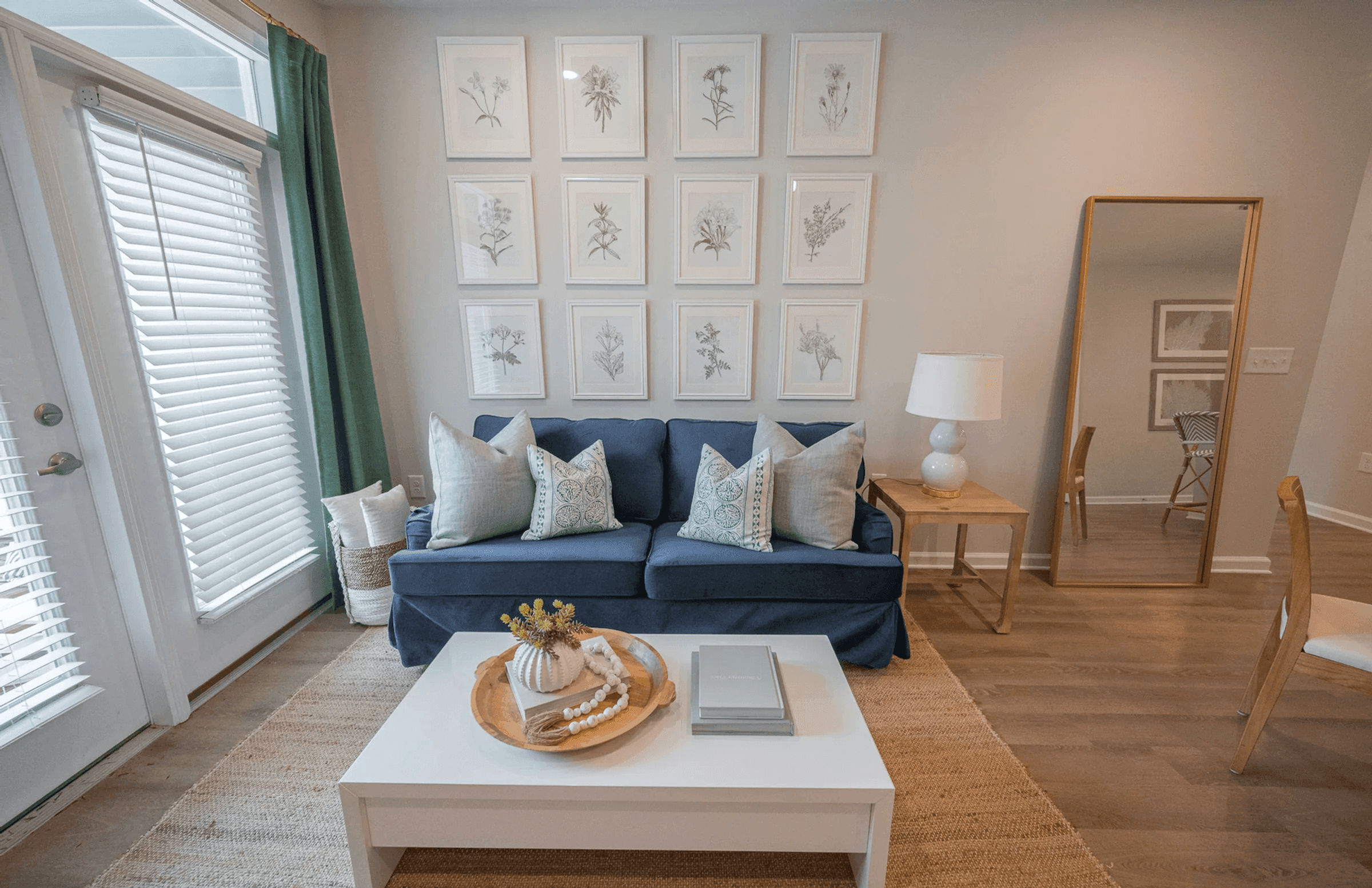 A living room with a blue couch, a white coffee table, and a mirror.