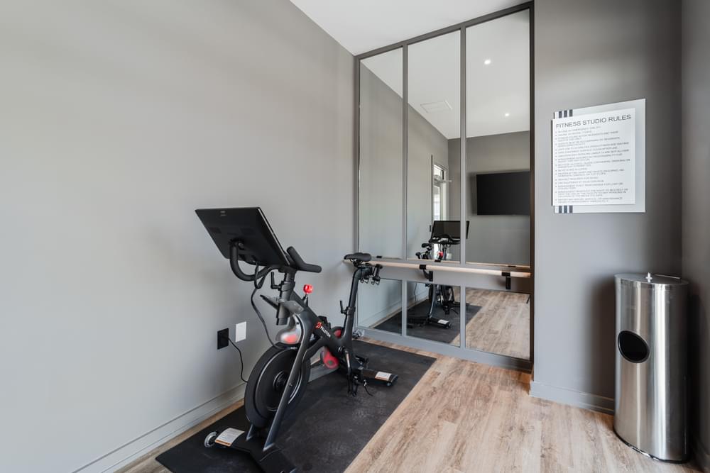 a workout room with a bike and a desk and a mirror