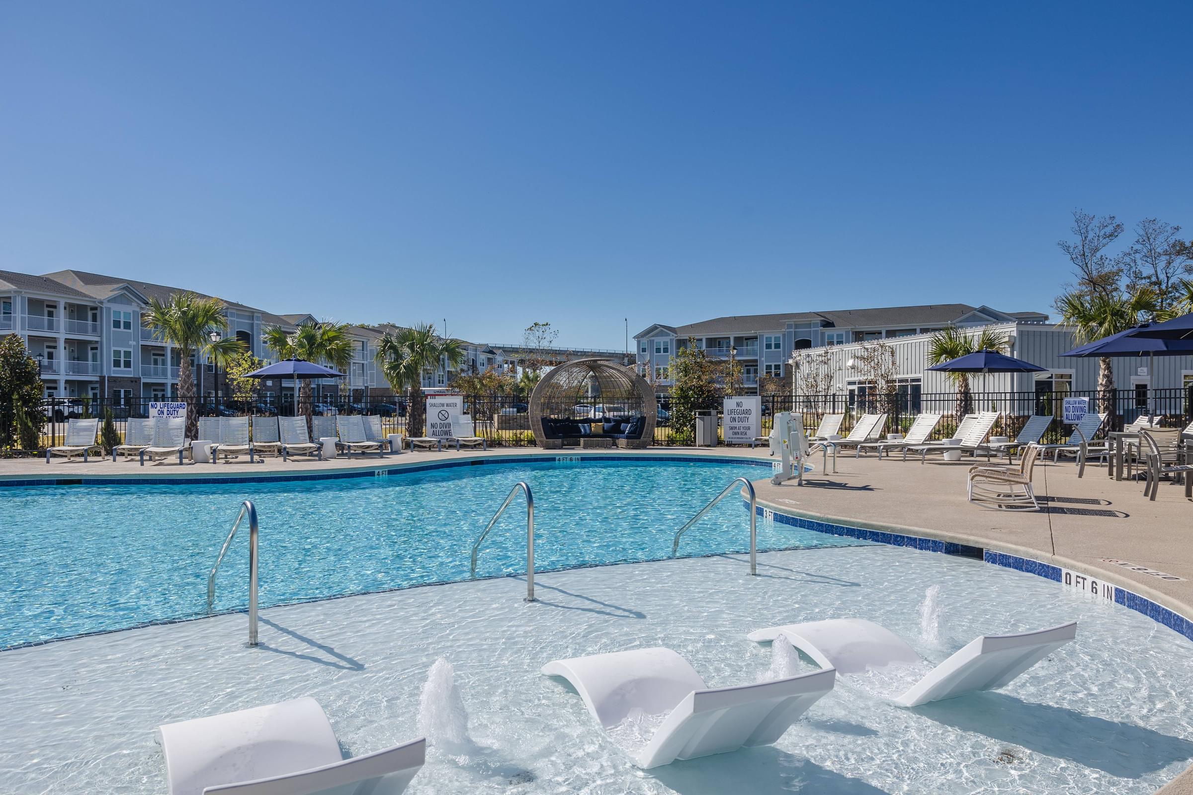 a swimming pool with chairs and umbrellas at the resort on a sunny day