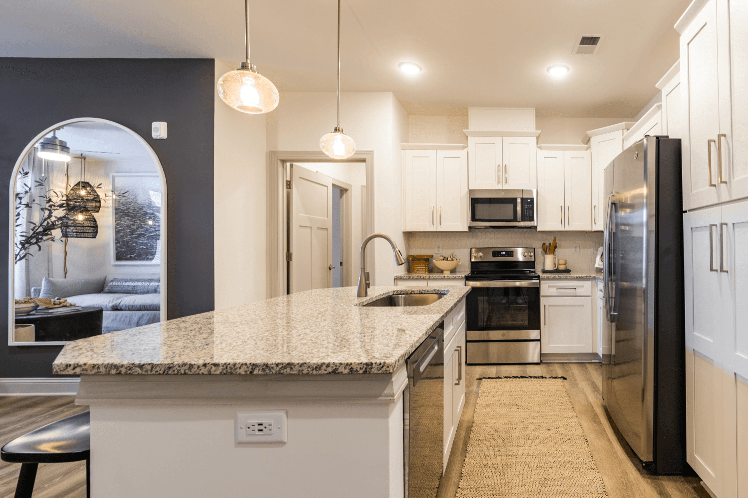 a kitchen with white cabinets and a marble counter top