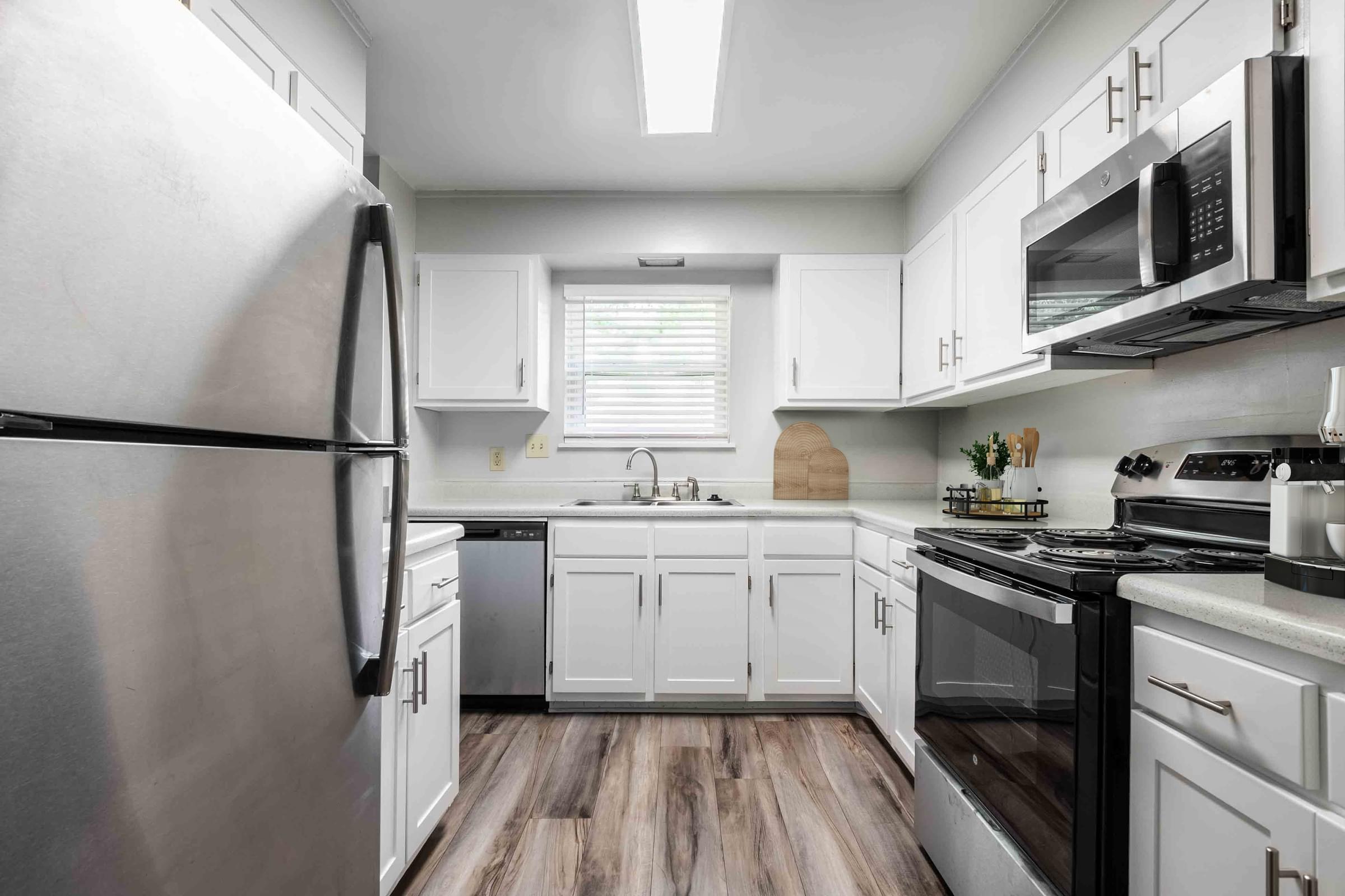 A kitchen with a refrigerator, microwave, oven, and sink.